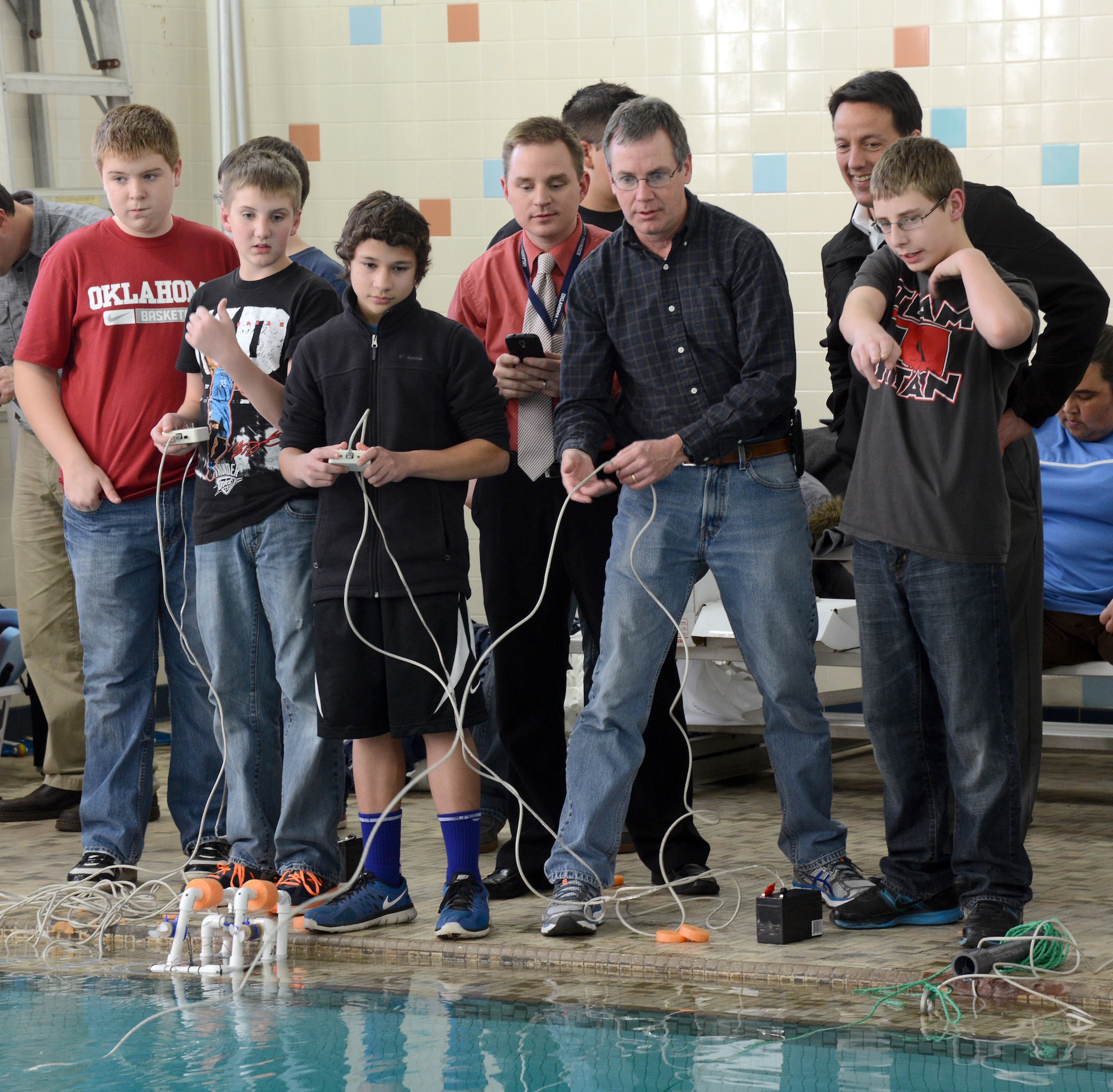 With the help of their Tinker mentors, Carl Albert Middle School students Matt Salsbury, Gregory Aldridge, Roshan Abhayagoonawardhana and Jakob Carlson, from left, work together to maneuver their SeaPerch Remotely Operated Vehicle through obstacles set up in the Midwest City YMCA pool last week. Watching the students are Don Arrowood, B-52 Program Office; Rich Desmond, 555th Software Maintenance Group; and Jeff Catron, Air Force Sustainment Center Engineering Directorate. (Air Force photo by Micah Garbarino)