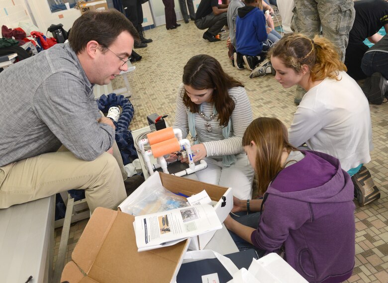 Rhett Butler, with the Air Force Life Cycle Management Center’s E3-AWACS Division, helps Sophia Smith, Hayley Allen and Elexis Speers, all eighth graders from Carl Albert Middle School, put the finishing touches on their SeaPerch ROV. (Air Force photo by Kelly White)