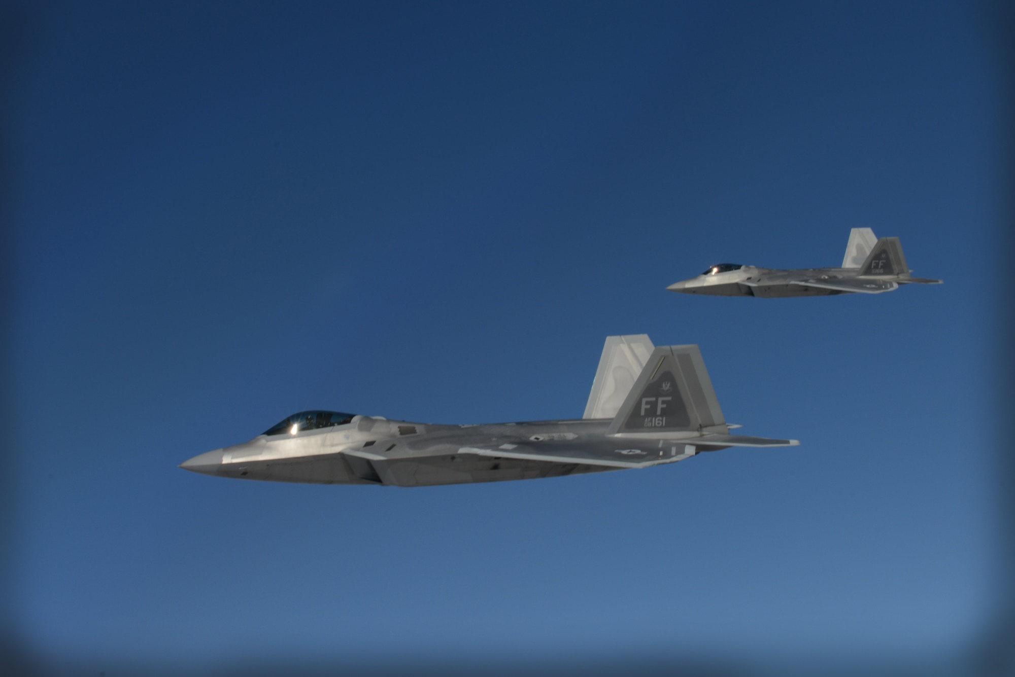 Two F-22 Raptors from the 1st Fighter Wing, Joint Base Langley-Eustis, Va., fly beside a KC-135 Stratotanker from the 93rd Air Refueling Squadron Fairchild Air Force Base, Wash., while waiting for their wingmen to receive fuel over the Nevada Test and Training Range during Red Flag 14-1 at Nellis AFB, Nev., Feb. 6, 2014. Red Flag gives aircrews and air support operations service members from various airframes, military services, and allied countries an opportunity to integrate and practice combat operations. (U.S. Air Force photo by Senior Airman Benjamin Sutton/Released) 