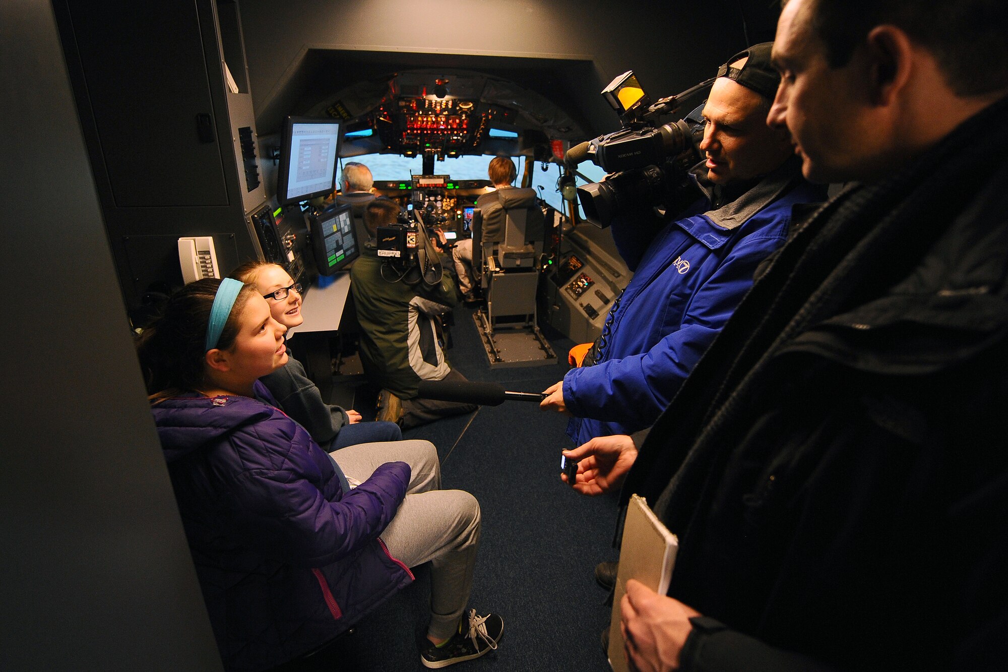 A photographer from a local television station interviews Ally Alexander (left) and Alaina Babbit (right), both students from Alfonza W. Davis Middle School located in Omaha, inside an aircraft simulator at Offutt Air Force Base, Neb. on Feb. 3. The students visited Offutt as part of the Offutt Flight Simulator Program that promotes education by inspiring students through experiences focused around science, technology, engineering and math. The program is sponsored by the Alfonza W. Davis chapter of Tuskegee Airmen Inc. (U.S. Air Force photo by Joshua Plueger/Released)