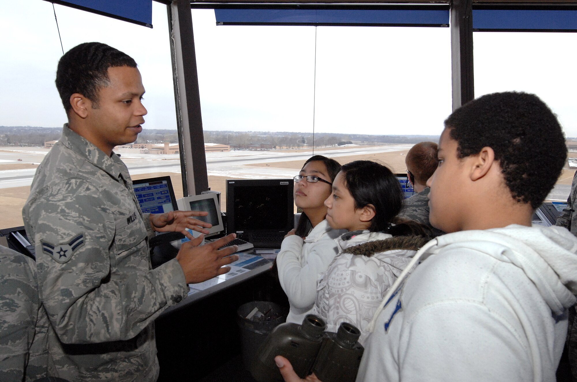 Airman First Class Chayce Willis, an air traffic controller from the 55th Operational Support Squadron, explains how aircraft landings and take offs are managed from the air traffic control tower to Maria Cruz (left), Pamela Garcia (middle), and Marcell Harper (right) inside the tower cab of the air traffic control tower at Offutt Air Force Base Neb. on Feb 3. The students toured the tower as part of the Offutt Flight Simulator Program that promotes education by inspiring students through experiences focused around science, technology, engineering and math. The program is sponsored by the Alfonza W. Davis chapter of Tuskegee Airmen Inc. (U.S. Air Force photo by Delanie Stafford/Released)
