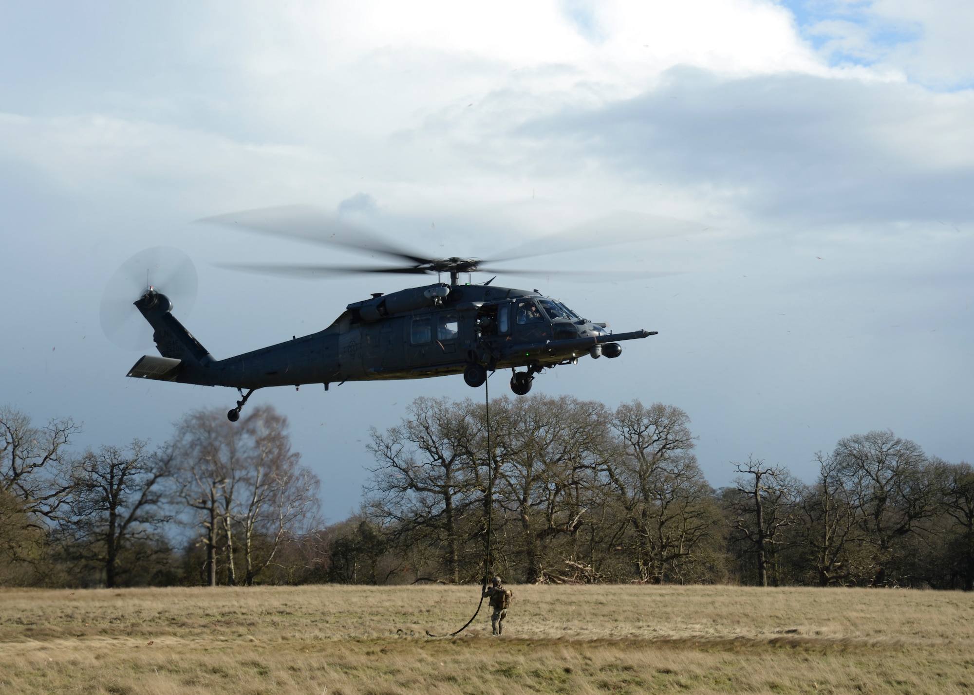 An HH-60G Pave Hawk helicopter drops a pararescue specialist during an exercise at the Stanford Training Area, England, Feb. 6, 2014. Airmen participated in four days of 56th Rescue Squadron training exercises in support of the Air Force’s combat search and rescue mission.  (U.S. Air Force photo by Airman 1st Class Nigel Sandridge/Released)