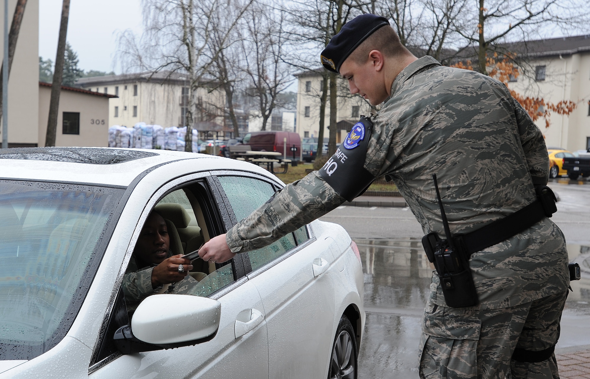 Airman 1st Class Christian Kampe, 86th Security Forces defender, hands an Airman her identification card after checking it at an entry way Feb. 5, 2014, Ramstein Air Base, Germany. Kampe is one of many first-term Airmen who are responsible for ensuring base operations run smoothly. (U.S. Air Force photo/Airman 1st Class Holly Mansfield)