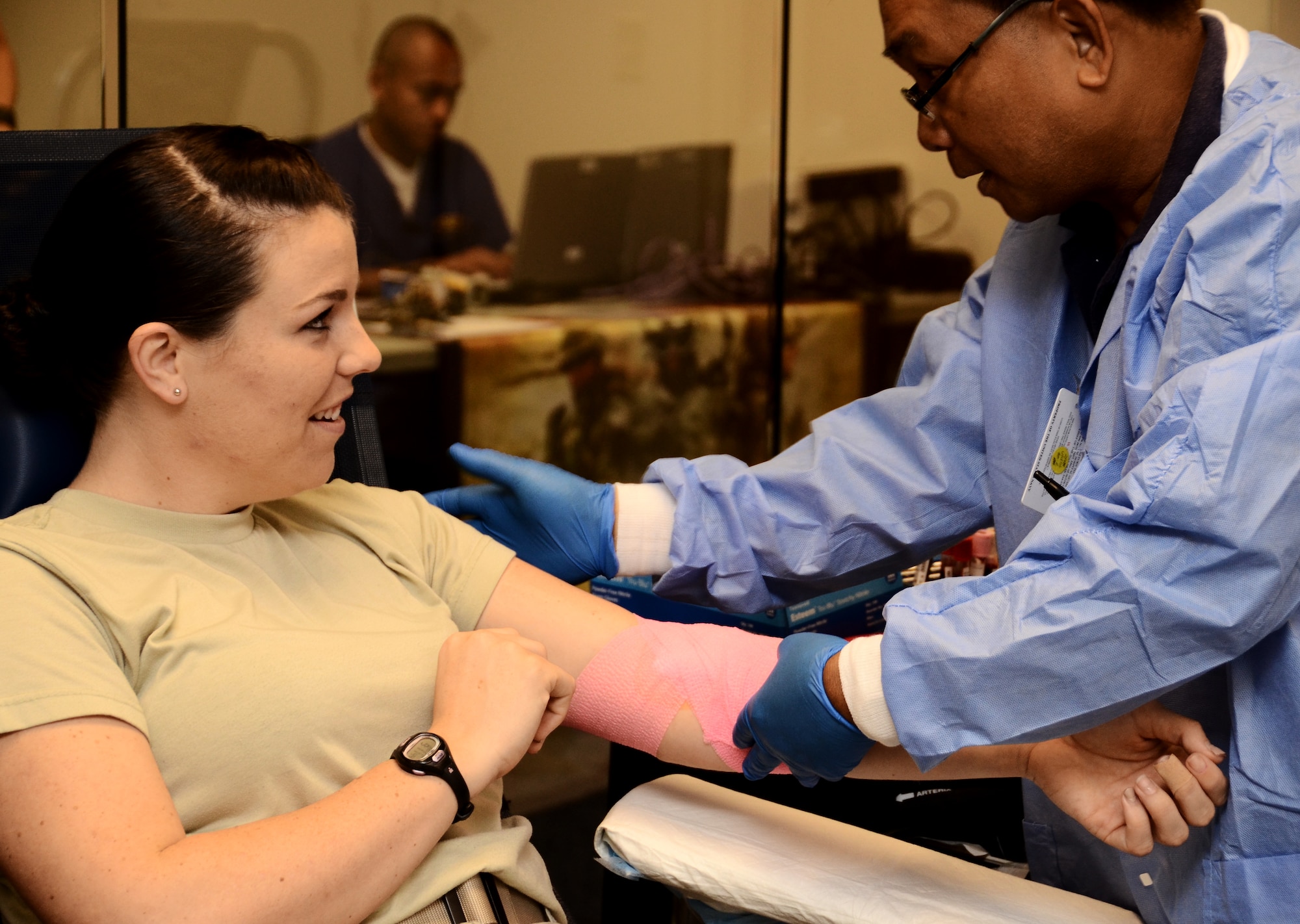 A U.S. Naval Hospital phlebotomist, thanks Senior Airman Elizabeth Silva, 36th Communications Squadron cyber transport technician, for her donation after applying a bandage to her arm during the 36th Contracting Squadron-sponsored blood drive Jan. 27, 2014. The Armed Services Blood Program estimates that one 500 milliliter donation has the potential to save up to three lives. (U.S. Air Force photo by Airman 1st Class Amanda Morris/Released)