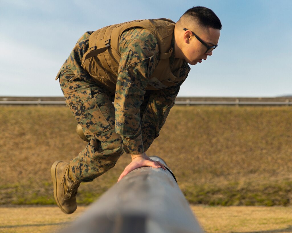 Cpl. Douglas Do, an administrative specialist with Headquarters and Headquarters Squadron, hurdles a log at the obstacle course during the Ironman Competition aboard Marine Corps Air Station Iwakuni, Japan, Feb. 5, 2014. Do was the team leader for Headquarters One, which placed 6th in the competition. 