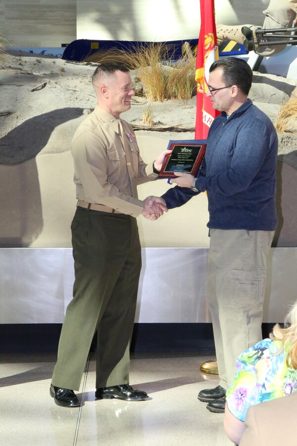 Col. David Maxwell, commanding officer of Marine Corps Base Quantico, presents M.V. Trindade, technical editor, Operations Analysis Division, Combat Development and Integration, with an award at the National Museum of the Marine Corps on Jan. 29, 2014. The OAD received recognition for Small Unit Winner, Most Improved; and Small Unit Winner, Highest Donations for the Potomac Combined Federal Campaign during 2013.