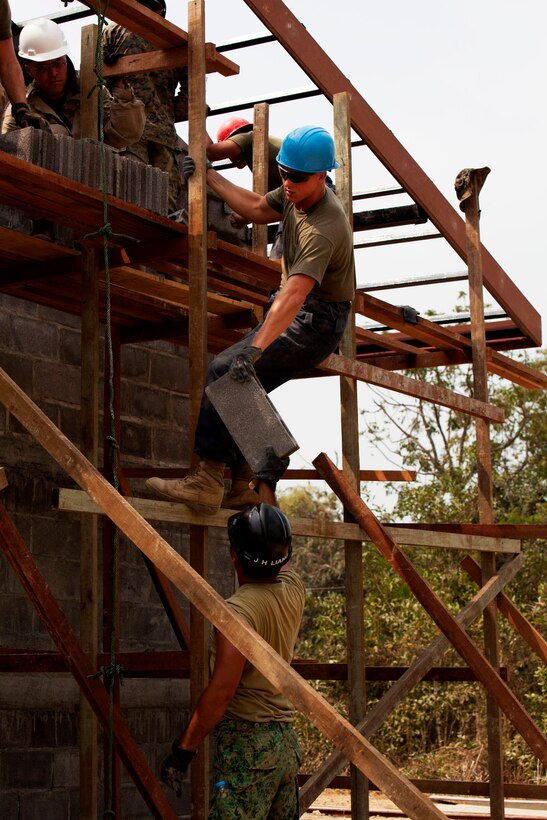 U.S. Marine Corps Cpl. Tristan Armstrong with Marine Wing Support Squadron 171, Marine Air Group 12, 1st Marine Aircraft Wing, III Marine Expeditionary Force, is handed a brick by a Singamore Soldier at the construction site at Ban Tabaek Ngam School in Bang Rakum, Phitsanulok, Kingdom of Thailand, on Feb. 7, 2014 in support of the exercise Cobra Gold 2014 (CG 14). CG 14, in its 33rd iteration, demonstrates the U.S. and the Kingdom of Thailand's commitment to their long-standing alliance and regional partnership, prosperity and security in the Asia-Pacific region.