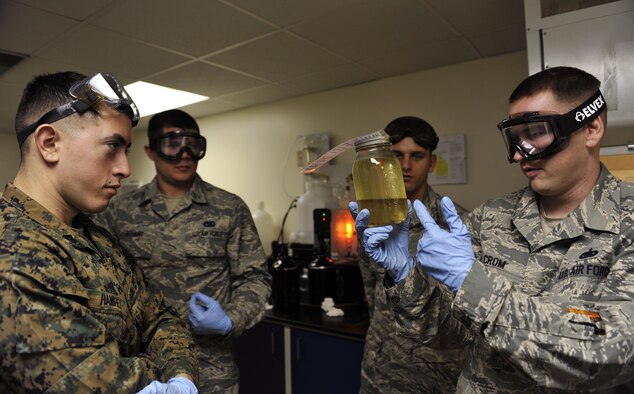 Tech. Sgt. Richard Crom presents a container of a fuel and water mixture during a field exchange program Feb. 6, 2014, at Kadena Air Base, Japan. The Field Exchange Program is the first of its kind which combines the Air Force and Marine Corps training on fuel procedures. Crom is the 18th Logistics Readiness Squadron NCO in charge of the fuel lab. (U.S. Air Force photo/Naoto Anazawa) 