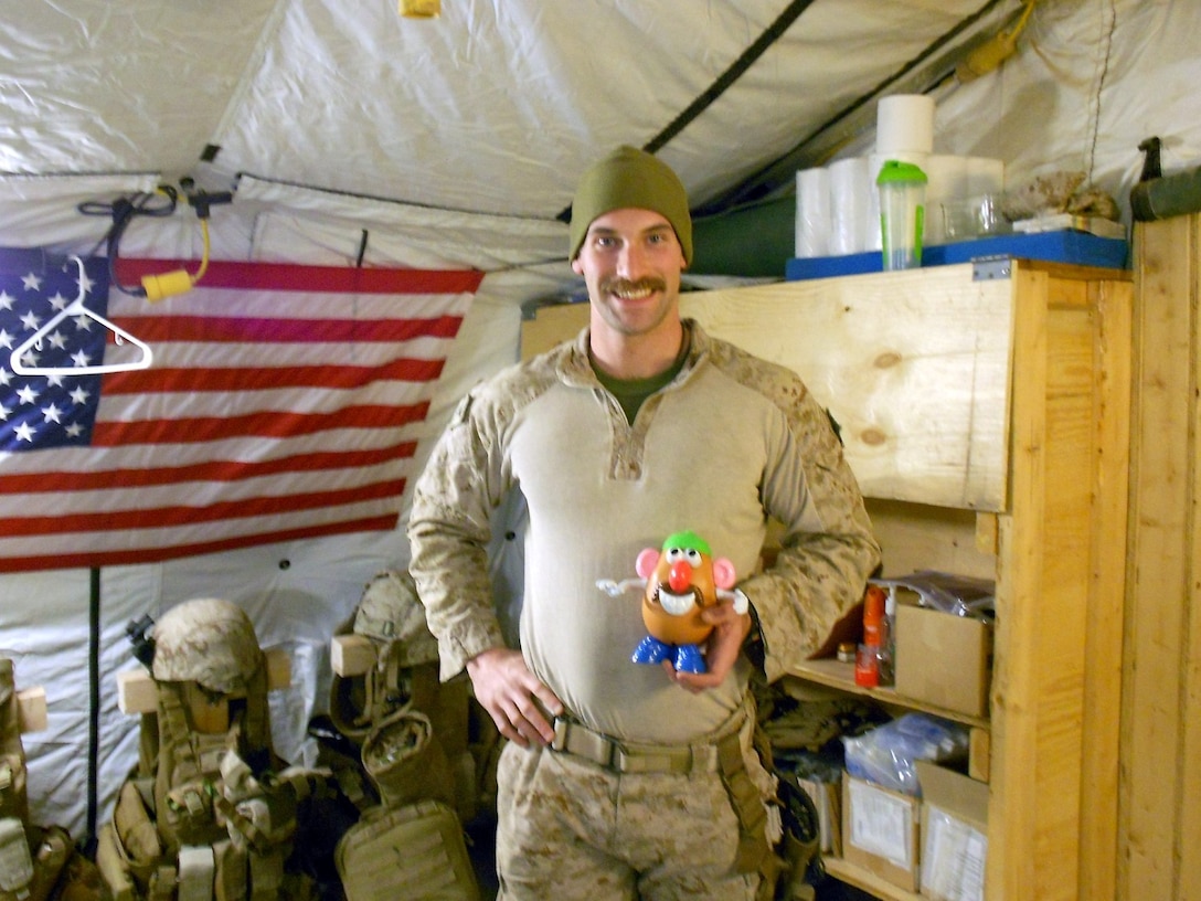 Petty Officer 3rd Class Kristopher Krysa, 27, from La Grange Park, Ill., a corpsman with Security Force Assistance Advisor Team 2-215, holds his Mr. Potato Head toy aboard Forward Operating Base Nolay, Helmand province, Afghanistan, Jan., 2014. Krysa obtained the Mr. Potato Head to help boost morale and keep everyone smiling.