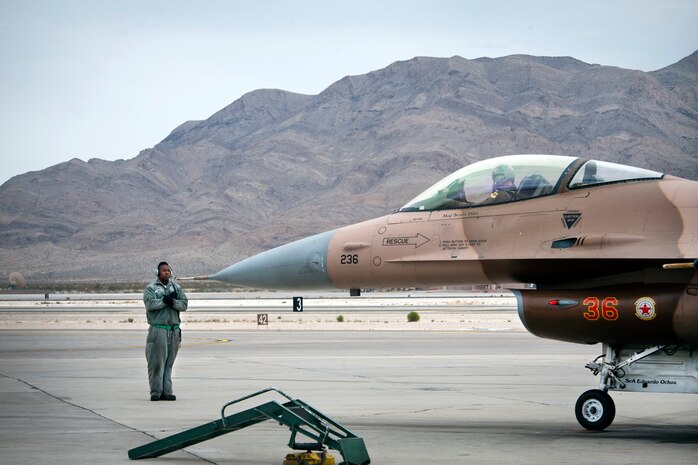 Tech. Sgt. Brian Savoy, 57th Aircraft Maintenance Squadron Viper Aircraft Maintenance Unit dedicated crew chief, prepares to marshal  an F-16 Fighting Falcon prior to a Red Flag 14-1 training mission Feb. 6, 2014, at Nellis Air Force Base, Nev. The 64th AGRS plays a critical role as the opposing air force during Red Flag by providing combat air forces from around the world challenges to prepare them for future conflicts or war. (U.S. Air Force photo by Lorenz Crespo)