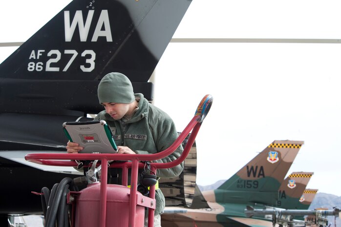 Airman 1st Class Colby Alexander, 57th Aircraft Maintenance Squadron Viper Aircraft Maintenance Unit avionics apprentice, reviews technical data on a 64th Aggressor Squadron F-16 Fighting Falcon prior to a Red Flag 14-1 training mission Feb. 6, 2014, at Nellis Air Force Base, Nev. Tactics the 64th AGRS use during Red Flag are designed to train pilots for a higher survivability rate within their first 10 sorties in combat situations. (U.S. Air Force photo by Lorenz Crespo)