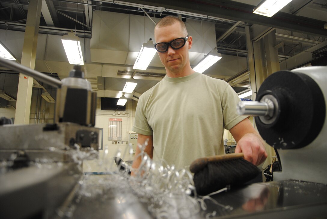 Staff Sgt. Edward James Broz, 69th Maintenance Squadron aircraft metals technology craftsman, sweeps aluminum scraps after making a metal bushing on a metal lathe Feb. 7, 2014, at the 69th MXS workshop on Grand Forks Air Force Base, N.D. Safety googles are worn from start to finish during shop projects and even during clean ups in order to avoid eye injuries. (U.S. Air Force photo/Staff Sgt. Luis Loza Gutierrez) 
