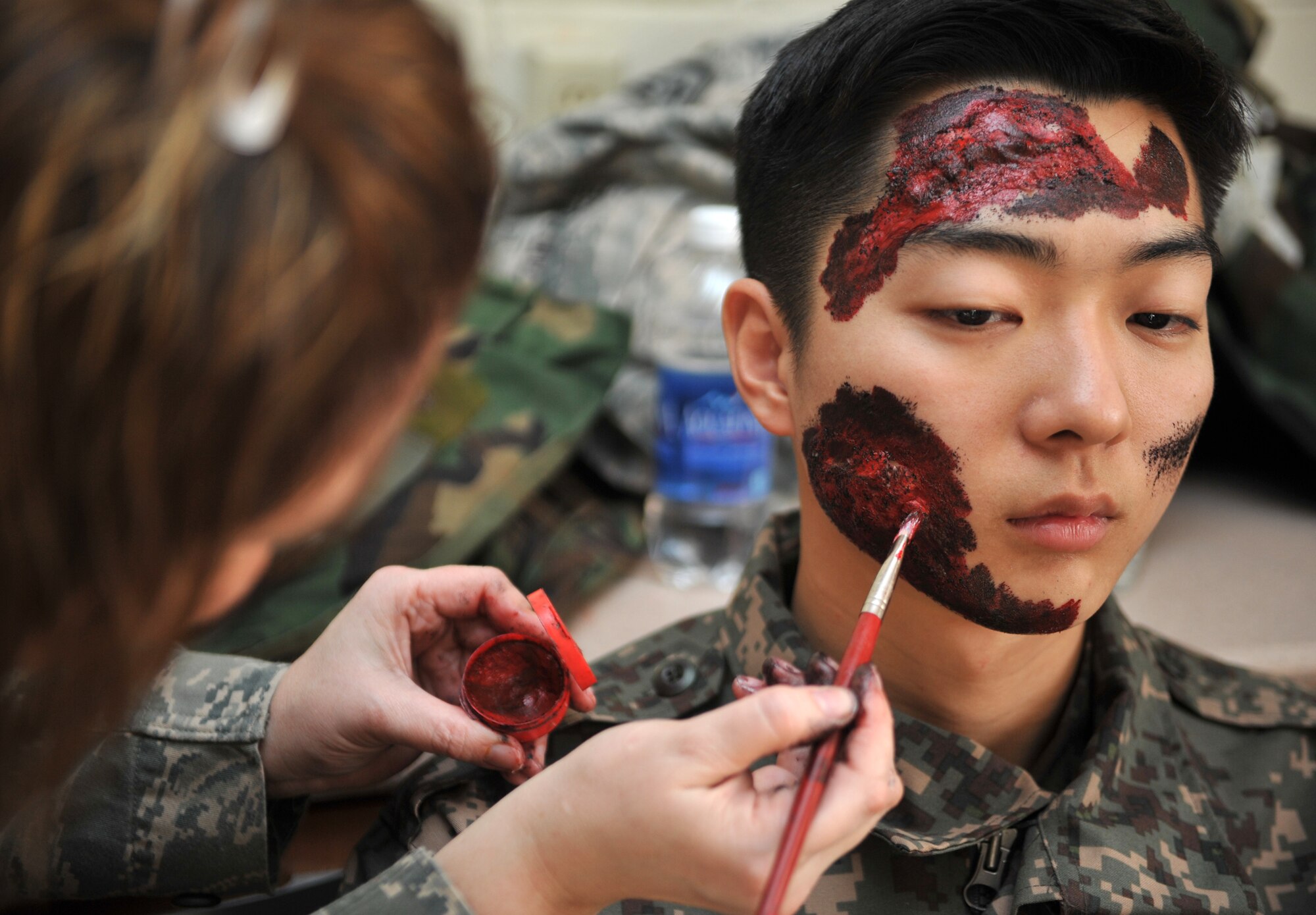 Master Sgt. Dawn Heydt, 51st Aerospace Medicine Squadron Public Health flight chief, creates mock lacerations on the face of Republic of Korea air force Airman 1st Class Jin Soo Kim, Air Police, in preparation for a mass casualty scenario during Operational Readiness Exercise Beverly Midnight 14-02 at Osan Air Base, ROK, Feb. 11, 2014. Medical personnel apply moulage makeup to role players during OREs to make mass casualty scenarios more realistic and test the self aid and buddy care skills of post-attack reconnaissance teams and the expertise of emergency medical teams. (U.S. Air Force photo/Airman 1st Class Ashley J. Thum)