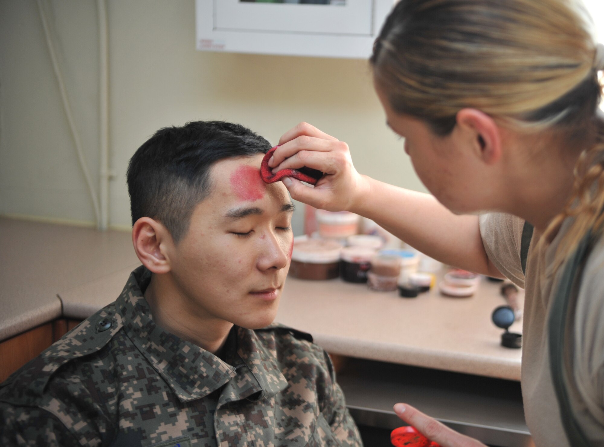 Staff Sgt. Therese Jimenez, 51st Medical Support Squadron medical logistics technician, applies moulage makeup to Republic of Korea air force Airman 1st Class Min Kim, Air Police, in preparation for a mass casualty scenario during Operational Readiness Exercise Beverly Midnight 14-02 at Osan Air Base, ROK, Feb. 11, 2014. Three ROKAF Airmen participated in the scenario as mock victims of a mortar attack. (U.S. Air Force photo/Airman 1st Class Ashley J. Thum)