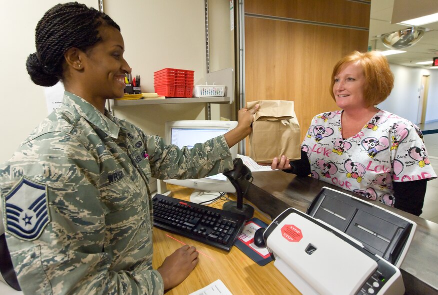 Master Sgt. Shakeera Wright, 436th Medical Group executive officer, hands medication to Jennifer Freeman, 436th Aerospace Medicine Squadron ophthalmic technician Feb. 11, 2014, at the pharmacy on Dover Air Force Base, Del. Wright won the 2013 Air Mobility Command Air Force Pharmacy Technician Noncommissioned Officer of the Year award. (U.S. Air Force photo/Roland Balik)