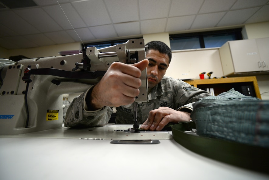 U.S. Air Force Senior Airman Jerry Salcido, 20th Operational Support Squadron aircrew flight equipment journeyman assigned to the 77th Fighter Squadron, works a sewing machine to repair a PCU-15B torso harness, Shaw Air Force Base, S.C., Feb. 11, 2014. The PCU-15B connects the pilot to the parachute in case of an emergency. (U.S. Air Force photo by Airman 1st Class Jonathan Bass/Released)
