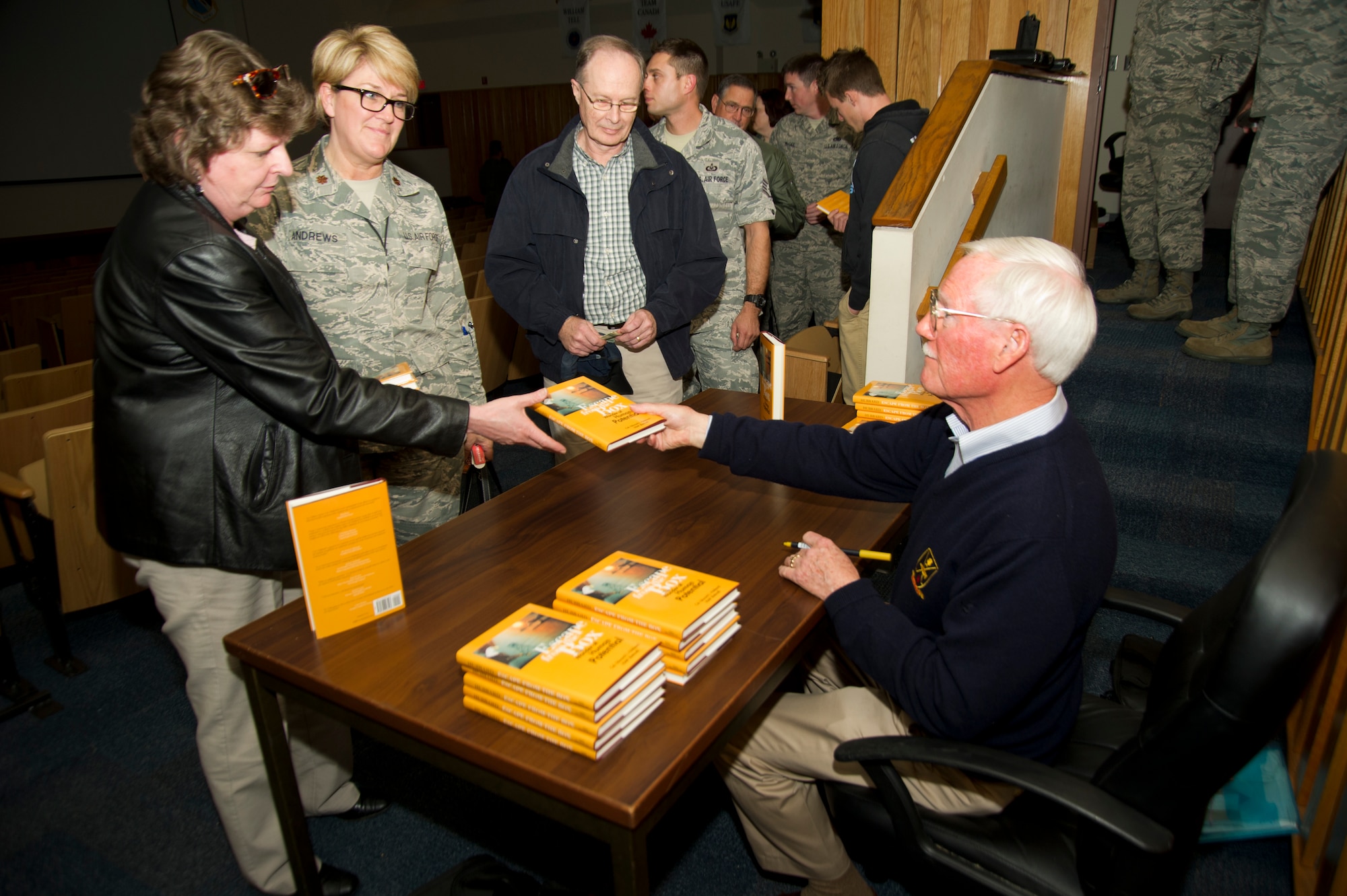Retired Col. Edward Hubbard, public speaker, signs copies of his book Feb. 7 in the 53rd Weapons Evaluation Group auditorium. Hubbard was a prisoner of war in Vietnam from 1966 to 1973, and now shares his experience to teach and inspire millions. (U.S. Air Force photo by Airman 1st Class Alex Echols)
