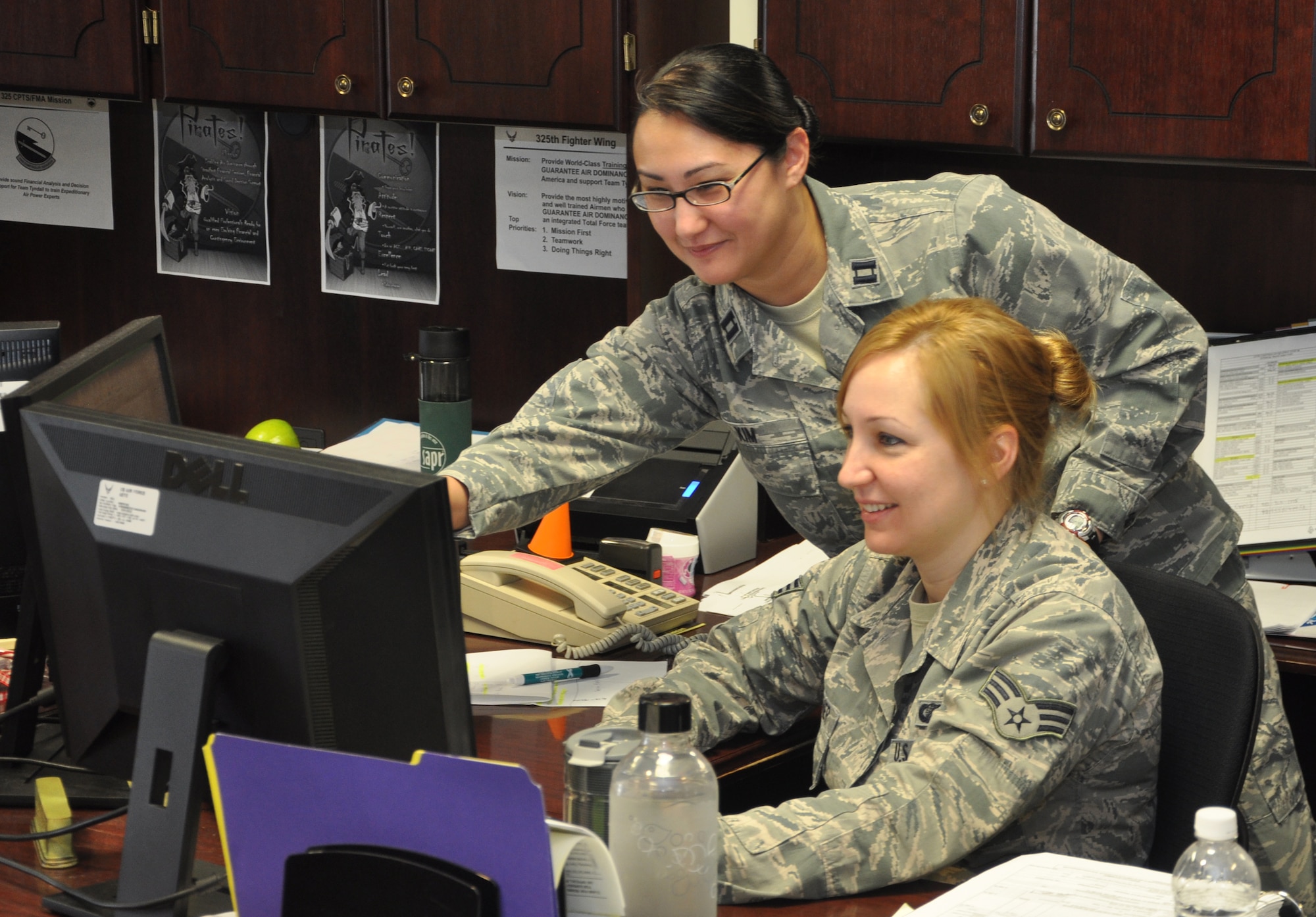 Capt. Michelle Kim, 325th Comptroller Squadron chief of financial analyst, assists Senior Airman Maria Faulkner, 325th CPTS financial analyst, with her work Feb. 11. Assisting and supervising Airmen is part of Kim’s day-to-day job. (U.S. Air Force photo by Airman 1st Class Solomon Cook)