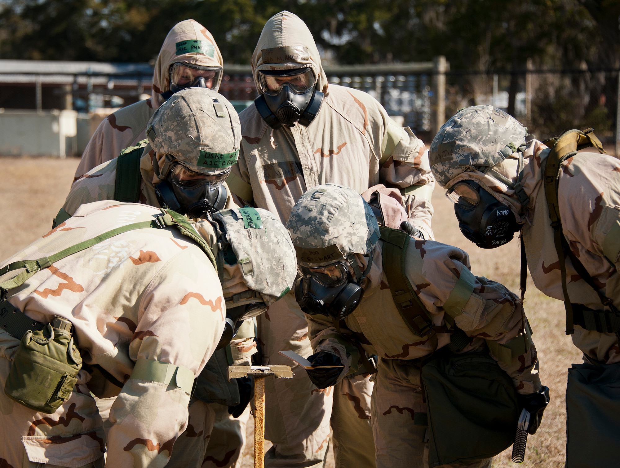 Airmen in MOPP-4 gear examine M8 contamination paper in their sector during the field training portion of a Phase II exercise Feb. 7 at Eglin Air Force Base, Fla. A Phase II evaluates an Airman’s ability to meet wartime and contingency taskings of employing the force, sustaining the force and the ability to survive and operate. More than 70 potential deployers received the classroom and practical field training during a series of 96th Test Wing exercises occurring all week. (U.S. Air Force photo/Sara Vidoni)