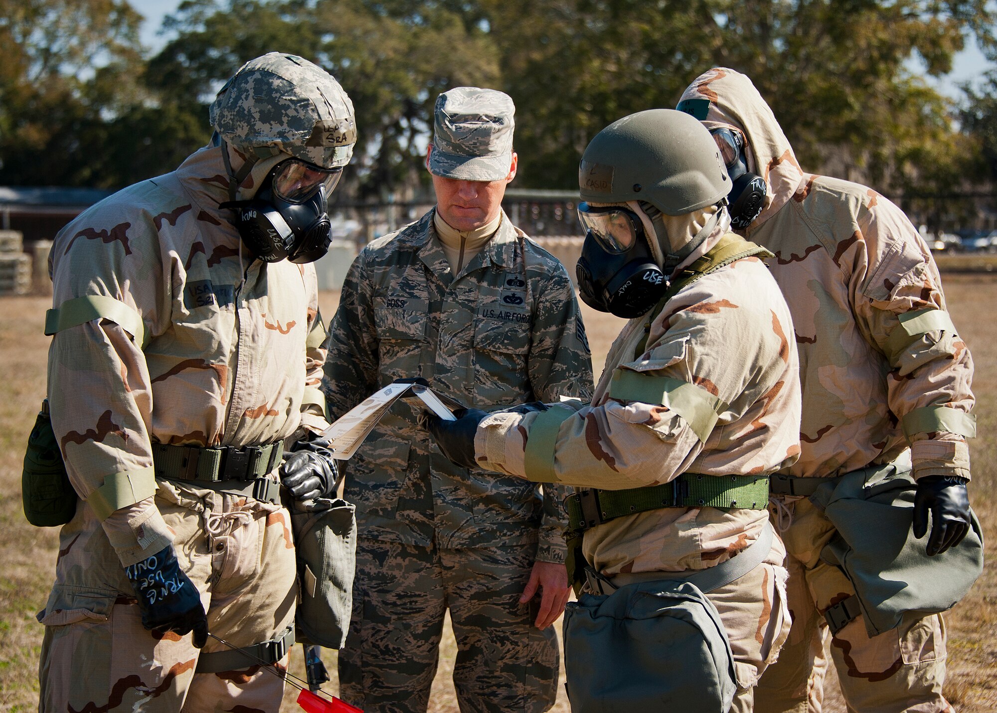 Staff Sgt. Shane Goss, of the 96th Civil Engineer Squadron, helps Airmen in MOPP-4 gear review the proper procedures for the next exercise during the field training portion of a Phase II exercise Feb. 7 at Eglin Air Force Base, Fla. A Phase II evaluates an Airman’s ability to meet wartime and contingency taskings of employing the force, sustaining the force and the ability to survive and operate. More than 70 potential deployers received the classroom and practical field training during a series of 96th Test Wing exercises occurring all week. (U.S. Air Force photo/Sara Vidoni)