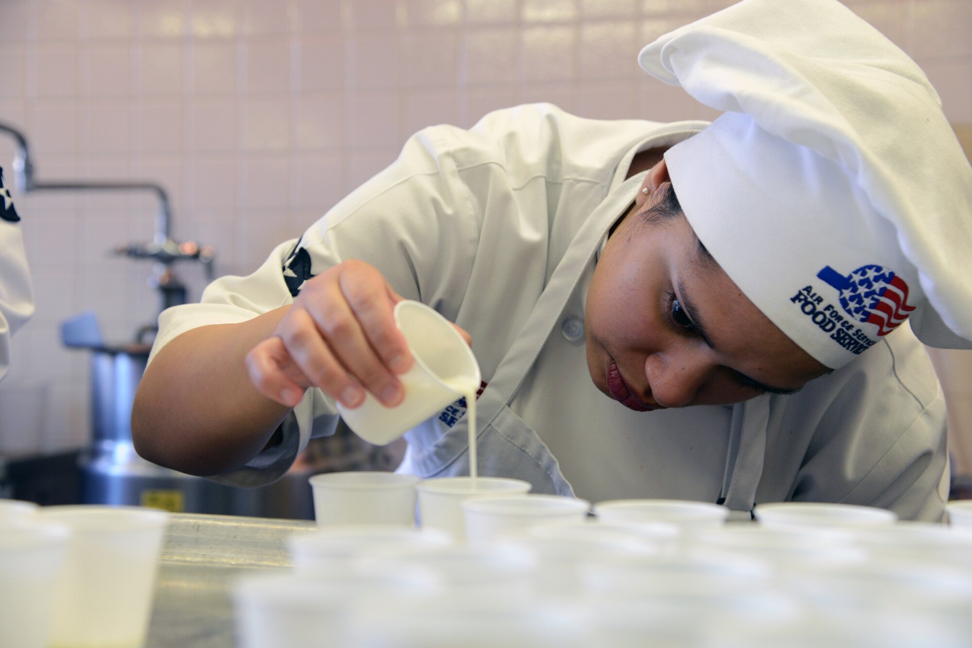 COLORADO SPRINGS, Colo. -- Airman Delia Reynolds, 21st Force Support Squadron, measures ingredients to make Freedom Feelers as she prepares for the annual Glass Slipper Ball, which took place Jan. 25. Reynolds, along with Airman 1st Class Shayla Bohrer, Senior Airman Candace Philippo and Airman 1st Class Bridget Mitchell, represented the Aragon Dining Facility. (U.S. Air Force photo/Tech. Sgt. Jared Marquis)