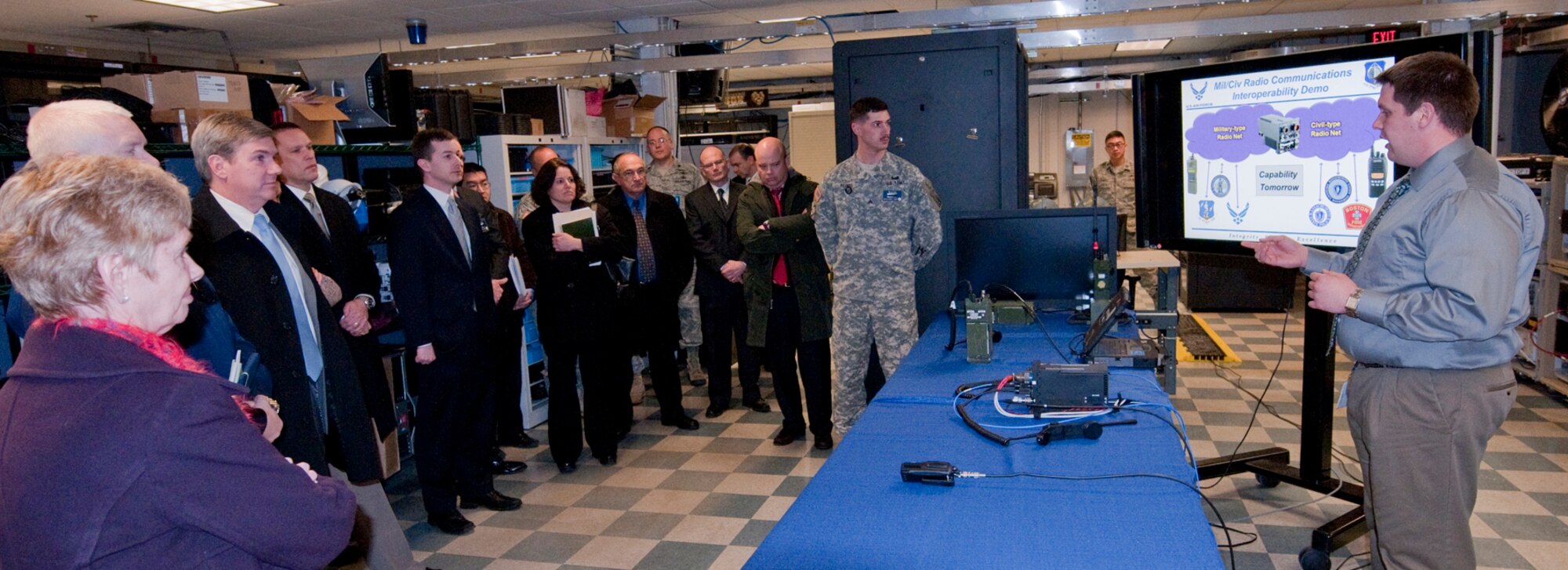 Zach Rose introduces a military-to-civilian radio interoperability demonstration to Mass. Secretary of Housing and Economic Development Gregory Bialecki, third from left, and other state and regional officials during a visit to Hanscom Air Force Base, Mass., Feb. 6. The group was touring a facility known as the CEIF, which is used to test and integrate advanced software, cyber, communications and network applications.  (U.S. Air Force photo by Steve O'Neil)