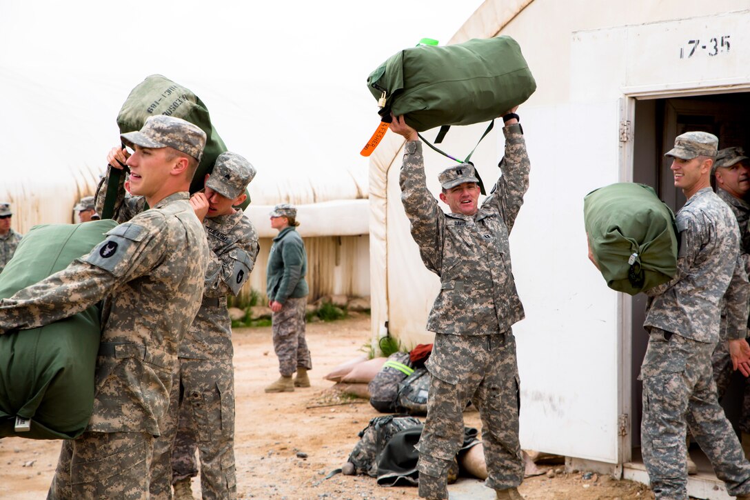 U.S. Army Cpt. Davis, center, presses a duffle bag overhead while soldiers load trucks and buses with the last of their gear before departing Camp Buehring, Kuwait, Feb. 3, 2014. Davis is assigned to the Montana Army National Guard's 1st Battalion, 189th General Support Aviation Battalion.