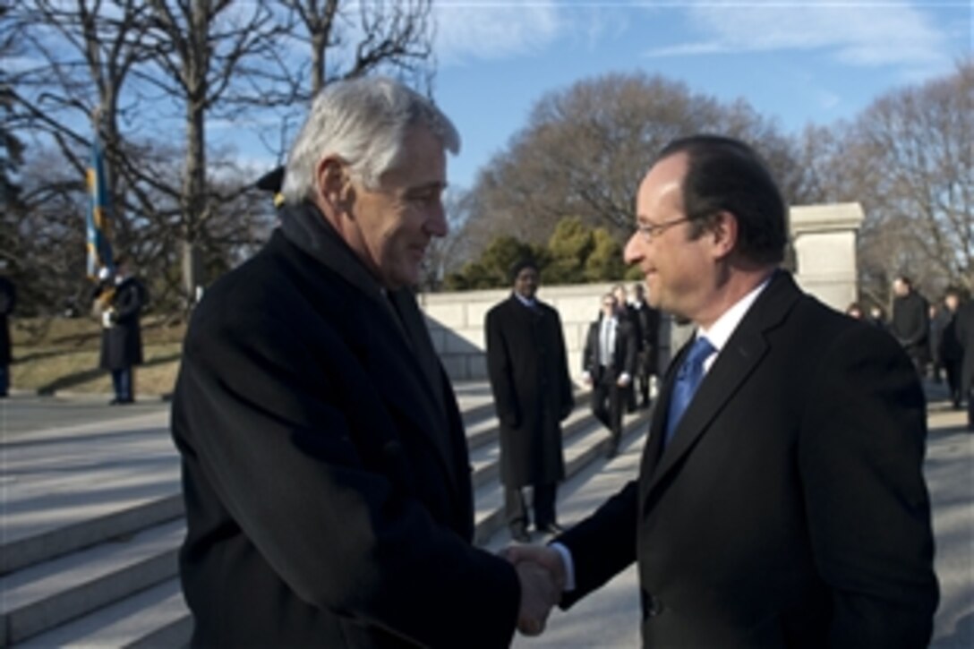 U.S. Defense Secretary Chuck Hagel greets French President Francois Hollande at Arlington National Cemetery in Arlington, Va., Feb. 11, 2014, before Hollande lays a wreath at the Tomb of the Unknowns and presents the World Ward II Unknown with the French Legion of Honor, France's highest military award.
