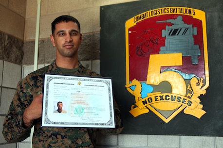 Corporal Jasdeep Singh, supply administrative chief, Combat Logistics Regiment 5, 1st Marine Logistics Group, displays his certificate of naturalization in front of the CLB-5 logo aboard Camp Pendleton, Calif., Feb. 4, 2014. Singh became a US citizen while serving in Afghanistan in 2012.