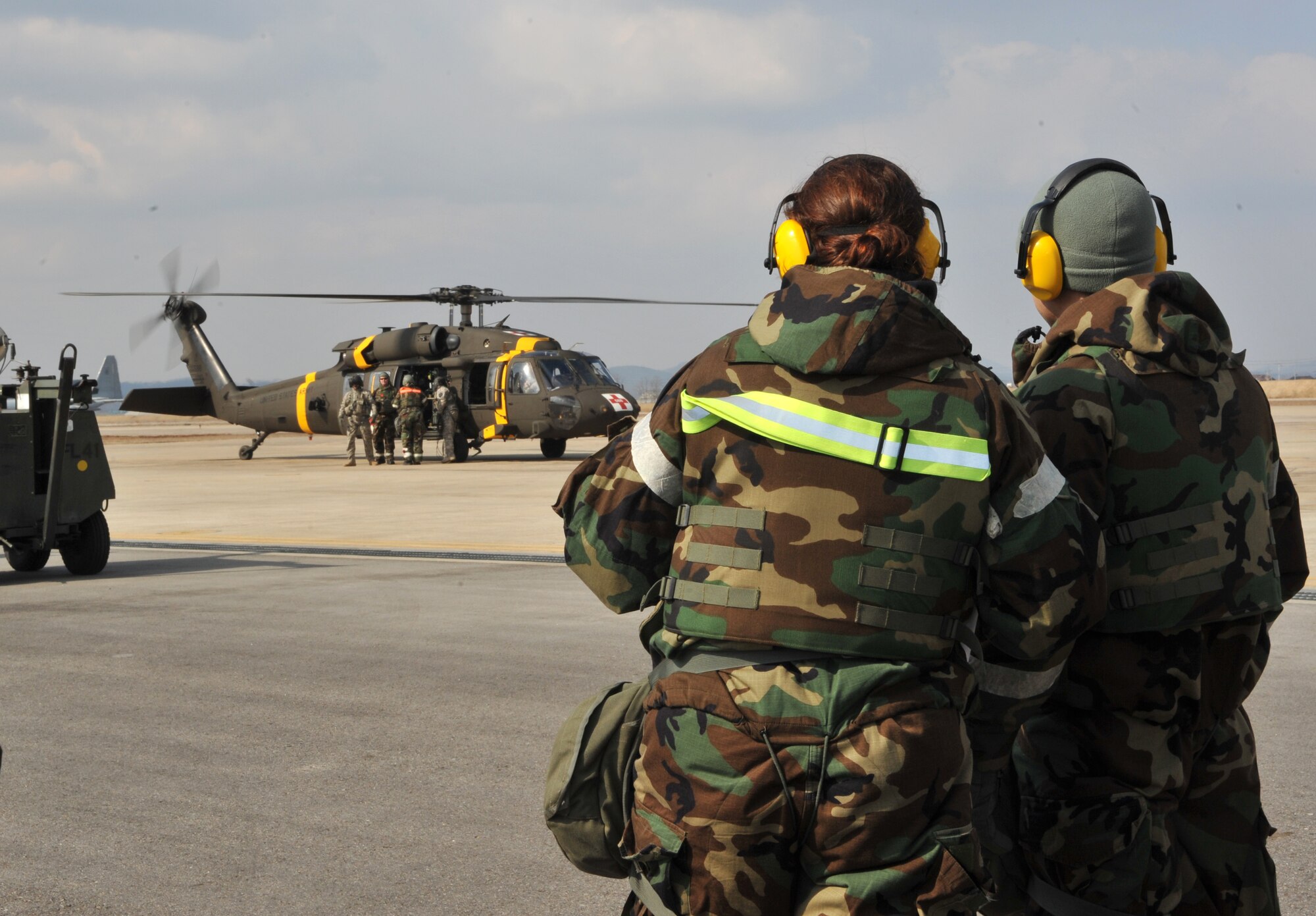 Tech. Sgt. Kimberly Cruickshank, 51st Aerospace Medicine Squadron flight medicine NCO in charge, left, and Capt. Peter Lee, 51st Dental Squadron general dentist, wait for the signal to approach a Black Hawk medevac helicopter from the 3rd General Support Aviation Battalion at U.S. Army Garrison Humphreys, Republic of Korea, during a medevac and dust-off scenario as part of Operational Readiness Exercise Beverly Midnight 14-02 at Osan Air Base, ROK, Feb. 12, 2014. The two were part of a four-person medical team that picked up five mock casualties from the helicopter’s three landings and loaded them into an ambulance for transport to the 51st Medical Group. (U.S. Air Force photo/Airman 1st Class Ashley J. Thum) 