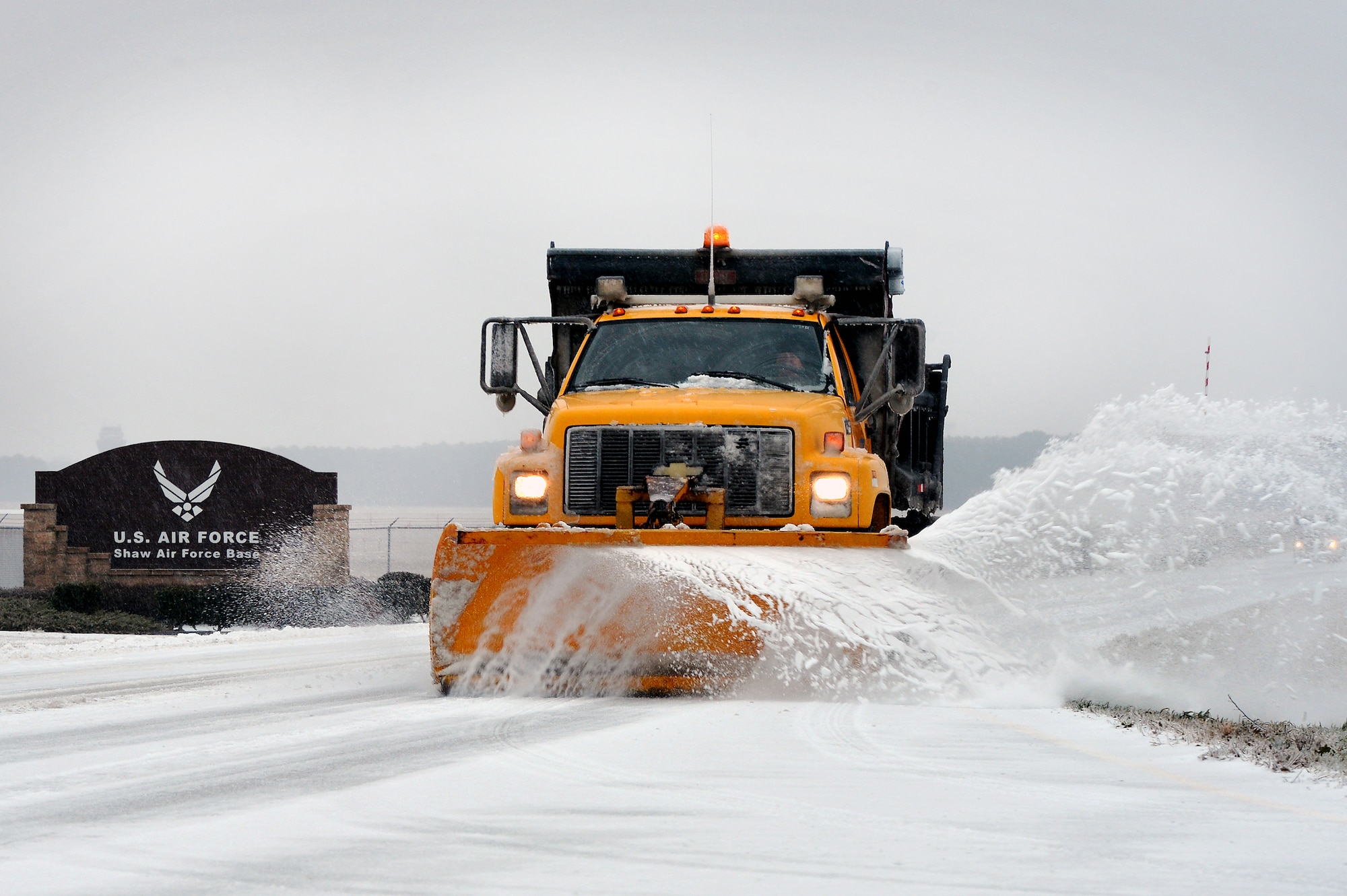 A snow plow truck removes snow and ice from Highway 378 just outside of the Shaw Air Force Base main gate, Feb. 12, 2014, Shaw Air Force Base, S.C. Though severe winter weather is rare at Shaw, this winter season has presented a fair amount of snow, sleet and ice. More than once this winter season, Shaw AFB has had to reduce its manning to "Mission Essential Personnel" only due to forecasted inclement weather. Team Shaw personnel are urged to stay off the roadways. Also, the 20th Fighter Wing safety team reminds all personnel to refer to winter safety tips when operating in the inclement winter environment. (U.S. Air Force Photo by Staff Sgt. Kenny Holston/Released) 