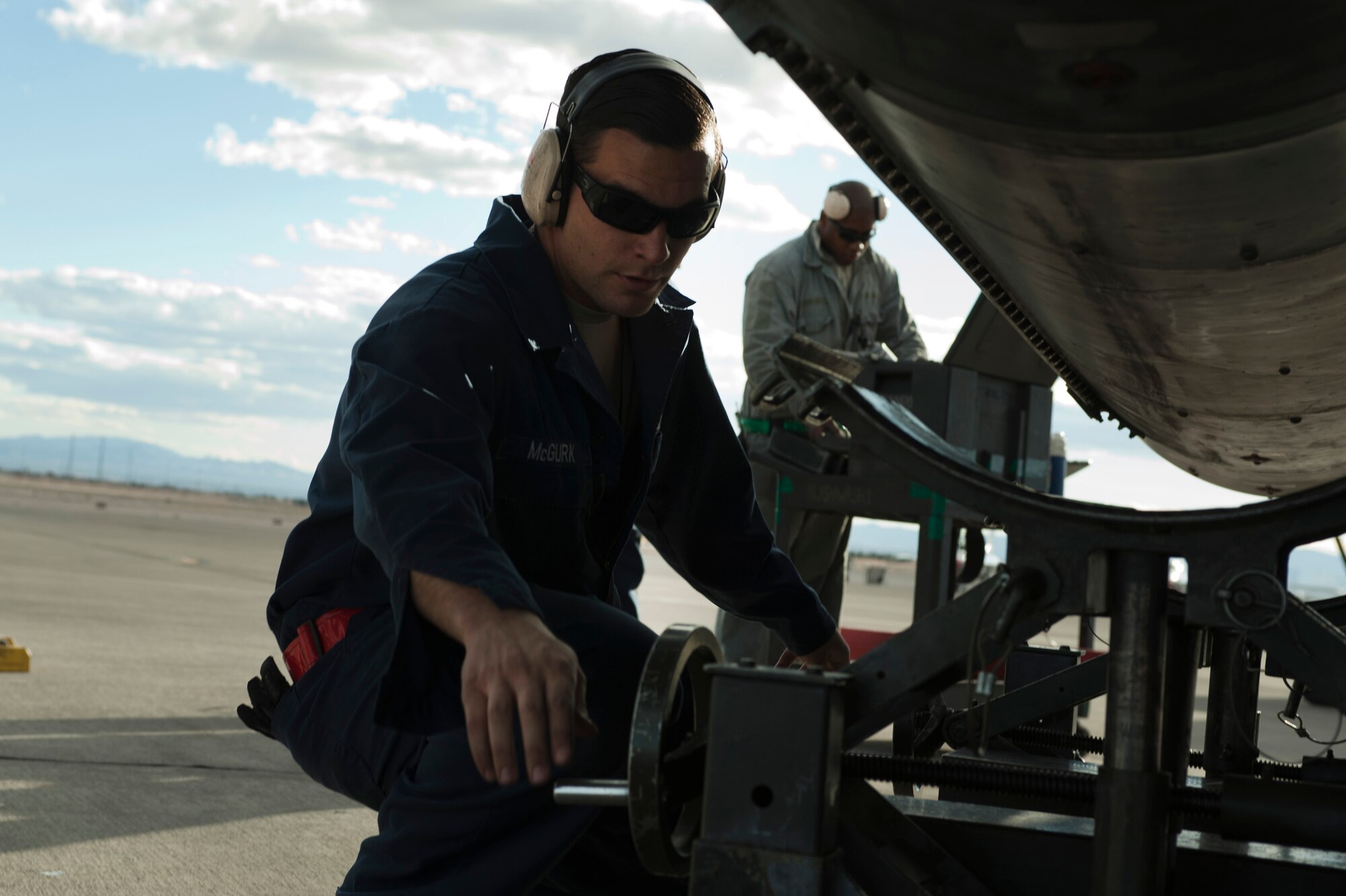 U.S. Air Force Tech Sgt. Donnie McGuark, 57th Aircraft Maintenance Squadron Viper Aircraft Maintenance Unit crew chief, lowers a lift used to install a new F-16 Fighting Falcon fuel tank on the flightline Feb. 10, 2014, at Nellis Air Force Base, Nev. The lift has a front and back crank in order to provide an easier installation of fuel tanks. (U.S. Air Force photo by Airman 1st Class Timothy Young)