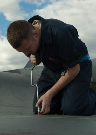 U.S. Air Force Staff Sgt. Jaymes Russell, 57th Aircraft Maintenance Squadron Viper Aircraft Maintenance Unit crew chief, tightens down a panel on an F-16 Fighting Falcon wing on the flightline Feb. 10, 2014, at Nellis Air Force Base, Nev. The panel was removed to expose the bolt used to attach the fuel tank. (U.S. Air Force photo by Airman 1st Class Timothy Young)