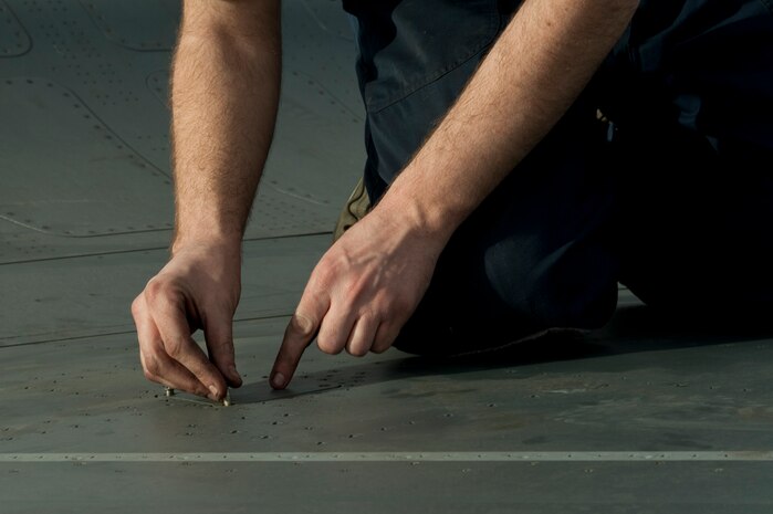 U.S. Air Force Staff Sgt. Jaymes Russell, 57th Aircraft Maintenance Squadron Viper Aircraft Maintenance Unit crew chief, places a panel back onto an F-16 Fighting Falcon on the flightline Feb. 10, 2014 at Nellis Air Force Base, Nev. The panel was removed to expose the bolt used to attach the fuel tank. (U.S. Air Force photo by Airman 1st Class Timothy Young)