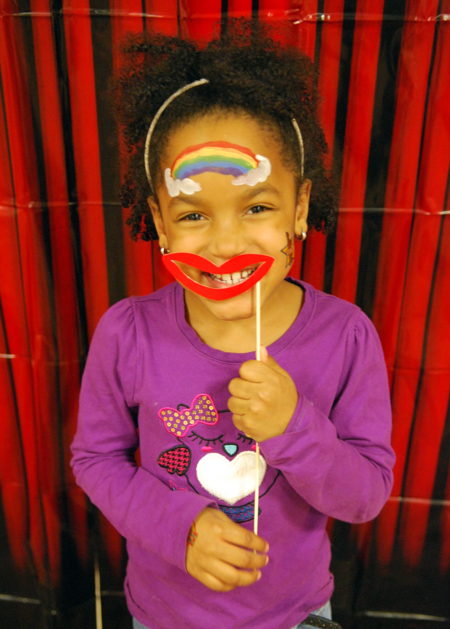 A young participant of Cannon Carnival holds her smile in place for the camera and carnival paparazzi picture during First Friday’s Cannon Carnival in the Landing Zone at Cannon Air Force Base, N.M., Feb. 7, 2014. With games, food and inflatable bouncy houses, the event attracted many members of the Cannon Family. (U.S. Air Force photo/Desiree Ann Montenegro)