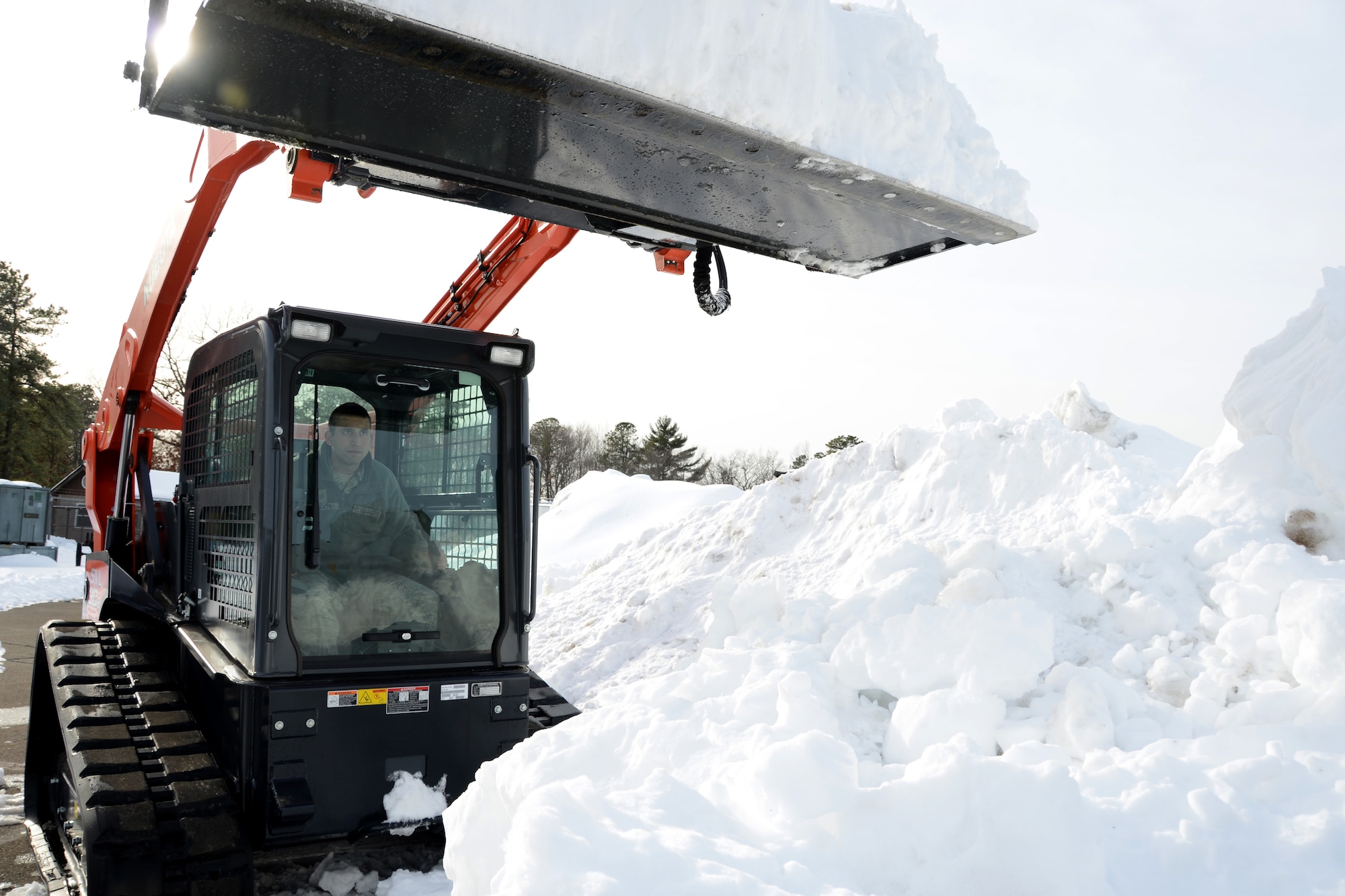 Senior Airman Christopher Cangemi, 103rd Civil Engineer Squadron, uses a new Kabota skid steer machine to clear snow from an accumulation point that could soon host additional snow expected to fall overnight on Feb. 12, 2014.  Despite their current high state of readiness and their proven track record of storm recovery service to the state and community, the unit will soon conduct a three-day course to train additional volunteers from other units of the Connecticut Air National Guard to increase the available pool of skilled team members for recovery operations in the event of a natural disaster, on or off base.  (U.S. Air National Guard photo by Master Sgt. Erin McNamara)