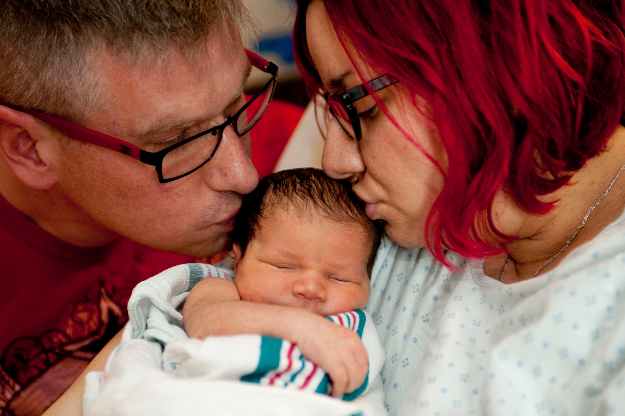 U.S. Air Force Master Sgt. William Dwyer, 1st Aircraft Maintenance Squadron inspector general self-assessment program manager, and his wife, Anita Dwyer, kiss their 3-day-old daughter, Constantina, at Langley Air Force Base, Va., Feb. 10, 2014. The Dwyers will spend their first Valentine’s Day as a family together. (U.S. Air Force photo by Staff Sgt. Stephanie R. Plichta/Released)