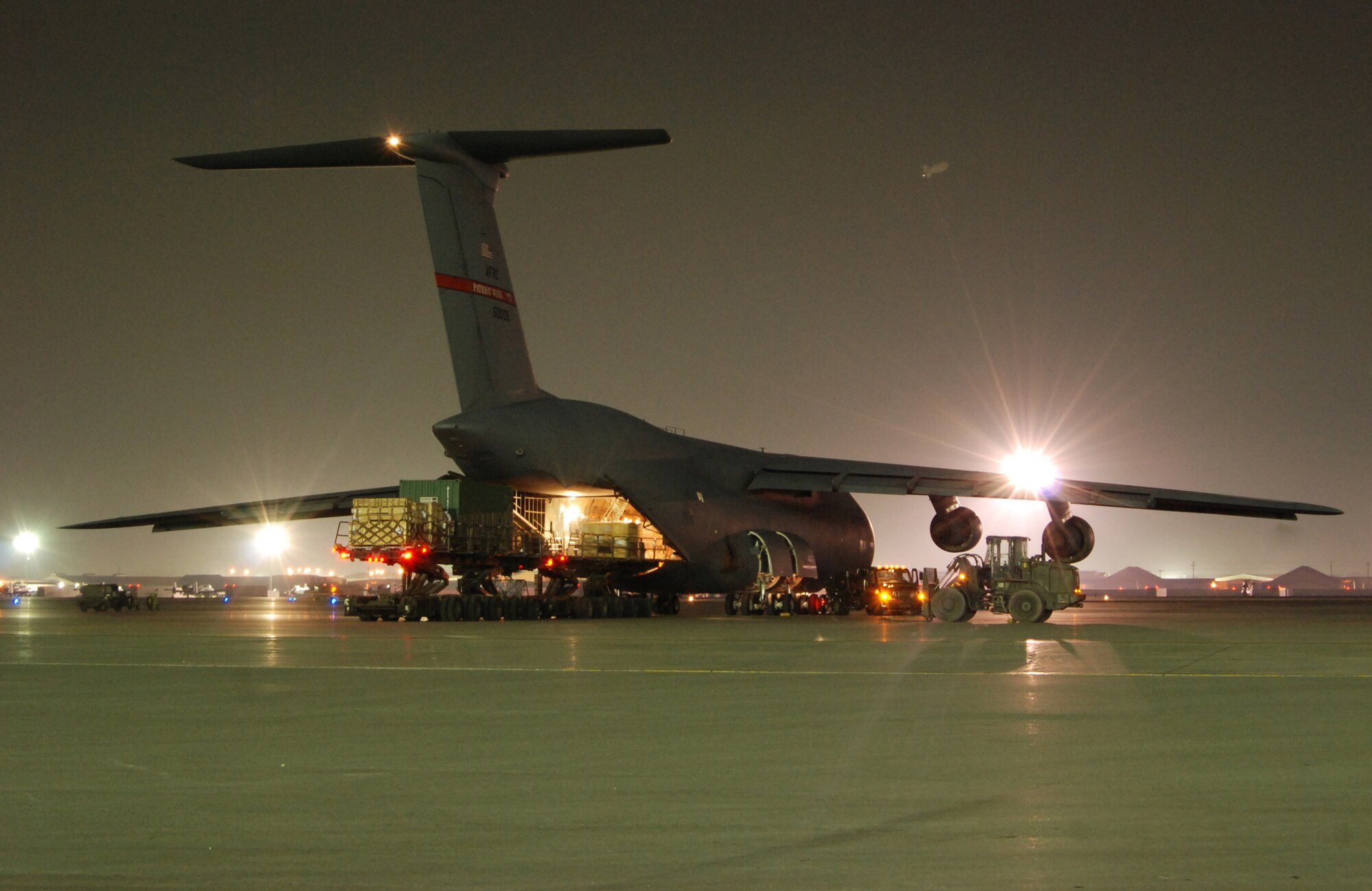 Two Tunner 60K loaders are parked in position to receive cargo from a C-5B Galaxy at Bagram Airfield, Afghanistan, Feb. 11, 2014. Aerial port Airmen off-loaded multiple pallets of cargo from the C-5, which is the Department of Defense’s largest military aircraft. (U.S. Air Force photo by Capt. Brian Wagner/Released)