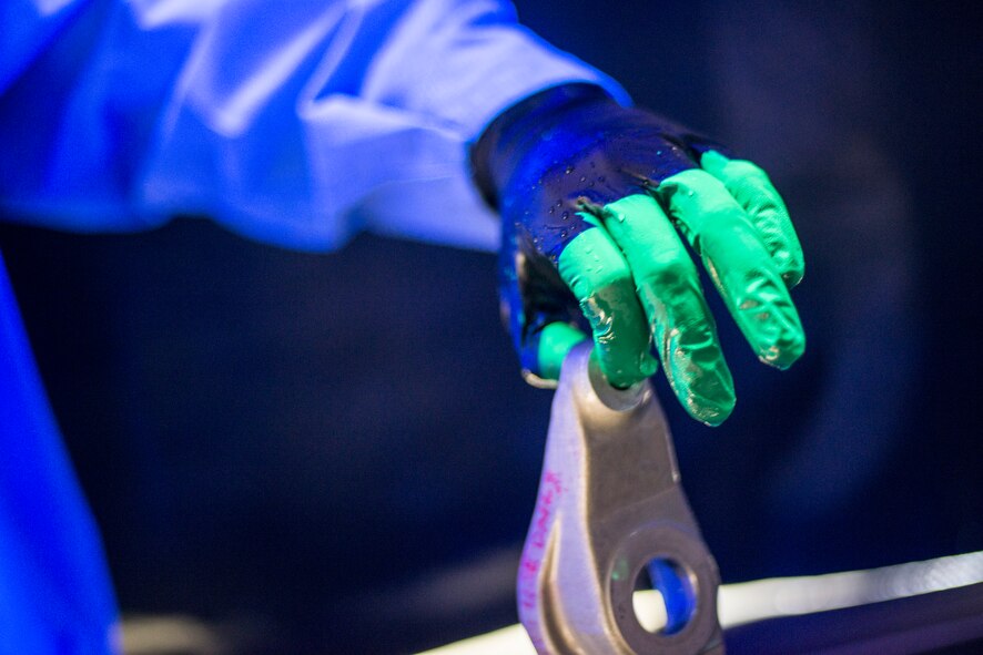 U.S. Air Force Airman Nicholas Burgess, 23d Equipment Maintenance Squadron non-destructive inspection apprentice, pulls a part from penetrant liquid at Moody Air Force Base, Ga., Feb. 11, 2014. After being submerged and dried, parts are inspected under blacklight for cracks and weak spots as a form of preventative maintenance. (U.S. Air Force photo by Airman 1st Class Ryan Callaghan/Released)
