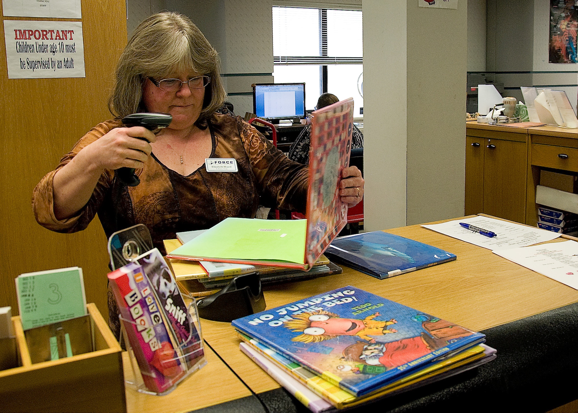 Elizabeth Hoard, 436th Force Support Squadron library aide, checks out books for a customer Feb. 4, 2014, at the base library on Dover Air Force Base, Del. The base library will transform into a virtual system March 21, 2014. (U.S. Air Force photo/Airman 1st Class Ashlin Federick)