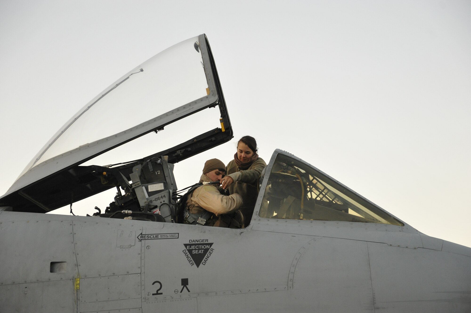 U.S. Air Force Capt. Patrick Parrish is buckled into the cockpit of his A-10 Thunderbolt II by Airman 1st Class Megan Brill before a mission at Bagram Airfield, Afghanistan, Feb. 11, 2014. Parrish is a native of Dublin, Ohio, and Brill is a native of Lacey, Wash. Both are deployed out of Moody Air Force Base, Ga.(U.S. Air Force photo by Senior Master Sgt. Gary J. Rihn/Released)