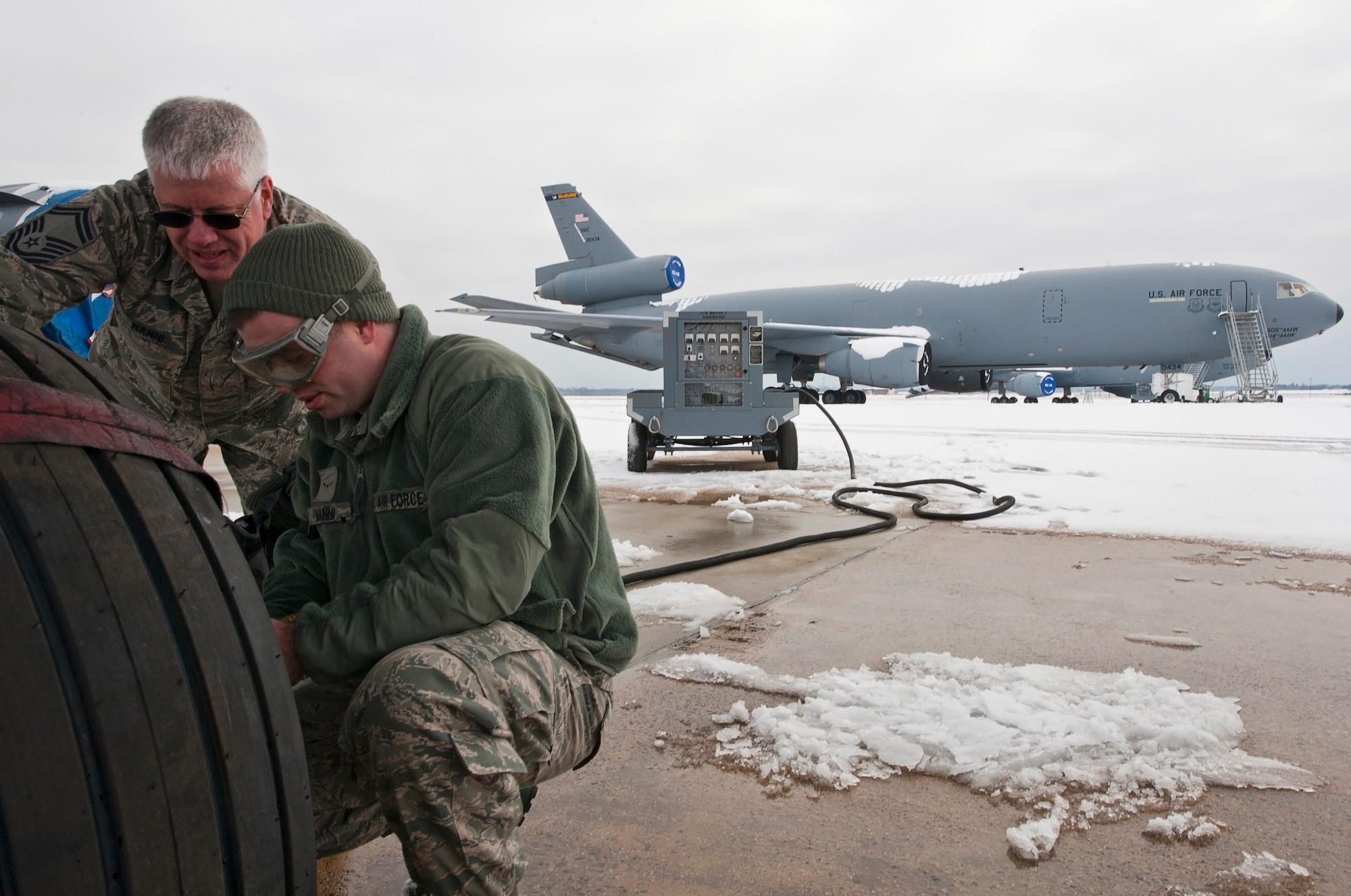 Master Sgt Anthony Nanni and Airman Andrew Nanni, 714th Aircraft Maintenance Squadron, check the tire pressure of a C-10 Globemaster II aircraft as part of the pre-flight inspection. The flight was the elder Nanni’s final fight of his career and the younger Nanni’s first. (U.S. Air Force photo by Christian DeLuca/released)