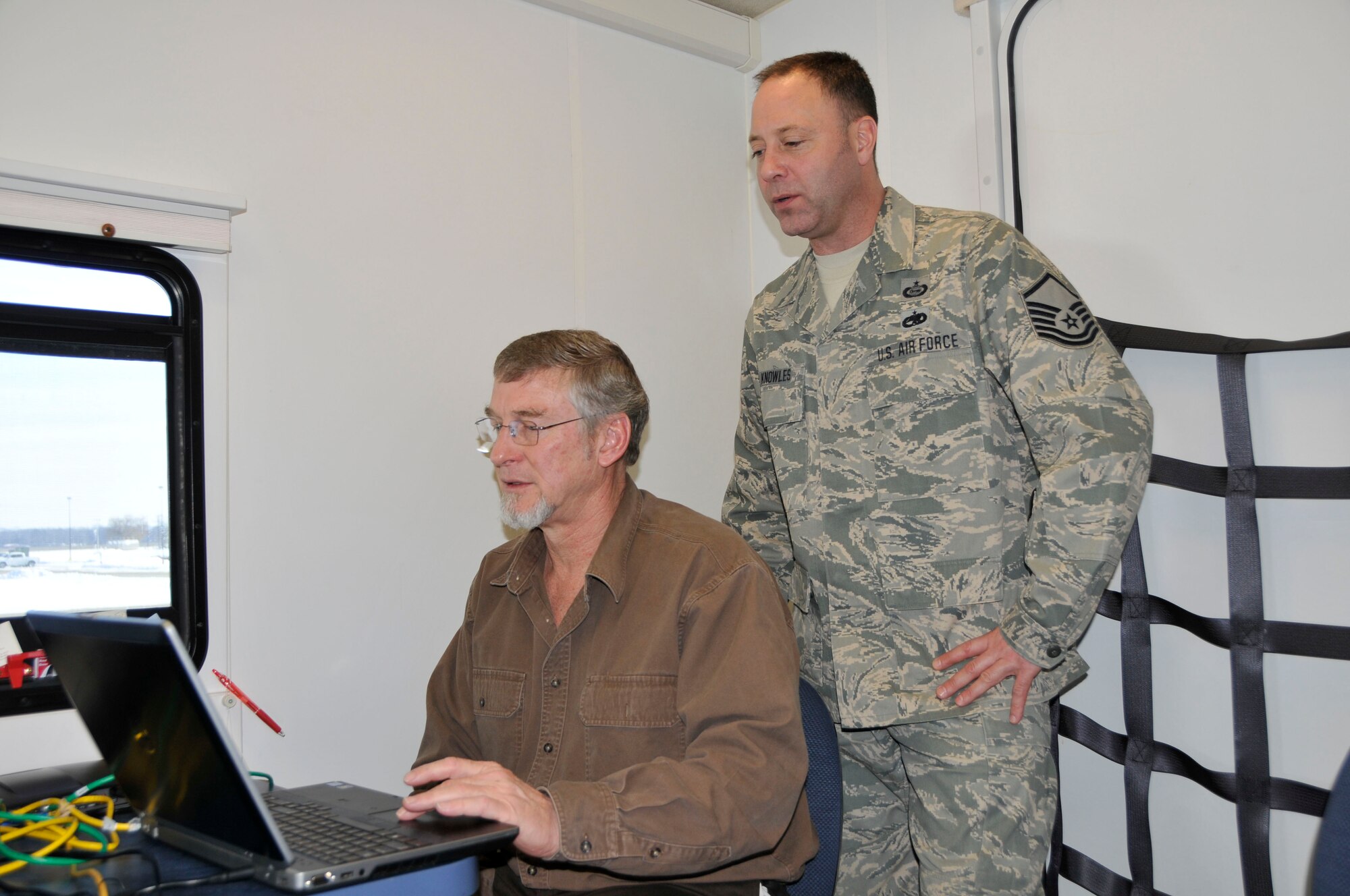 U.S. Air Force Master Sgt. Ben Knowles, 181st Intelligence Wing, Indiana Air National Guard and Mr. Doug Reinbold, Readjustment Counseling Technician, Veterans Center look at imagery sent down into the Mobile Vet Center, Feb 6, 2014 Hulman Field, Terre Haute, Ind. In a natural disaster these images would be given to the incident commander to better prepare for recovery efforts. (U.S. Air National Guard photo by Senior Master Sgt. John S. Chapman/Released)
