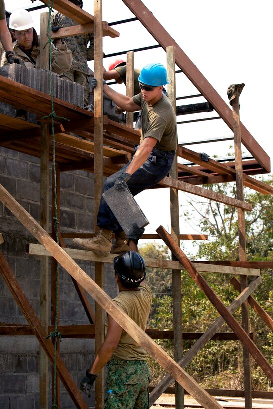 U.S. Marine Cpl. Tristan Armstrong, top, gets a brick from a member of the Singapore armed forces at a construction site during Cobra Gold 2014 at Ban Tabaek Ngam School in Phitsanulok, Thailand, Feb. 7, 2014. Armstrong is assigned to Marine Wing Support Squadron 171, Marine Aircraft Group 12, 1st Marine Aircraft Wing, 3rd Marine Expeditionary Force.