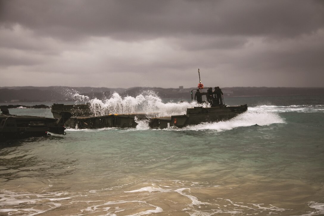 Marines observe as a bay from the new improved ribbon bridge splashes open at Camp Schwab, Feb. 6 during new equipment training. The five days of training enabled the Marines to build on their previous knowledge of
bridges and learn the fundamentals of the IRB and Marine Corps bridge pallet system. The Marines are with 9th
Engineer Support Battalion, 3rd Marine Logistics Group, III Marine Expeditionary Force. Photo by Cpl. Anne K. Henry
