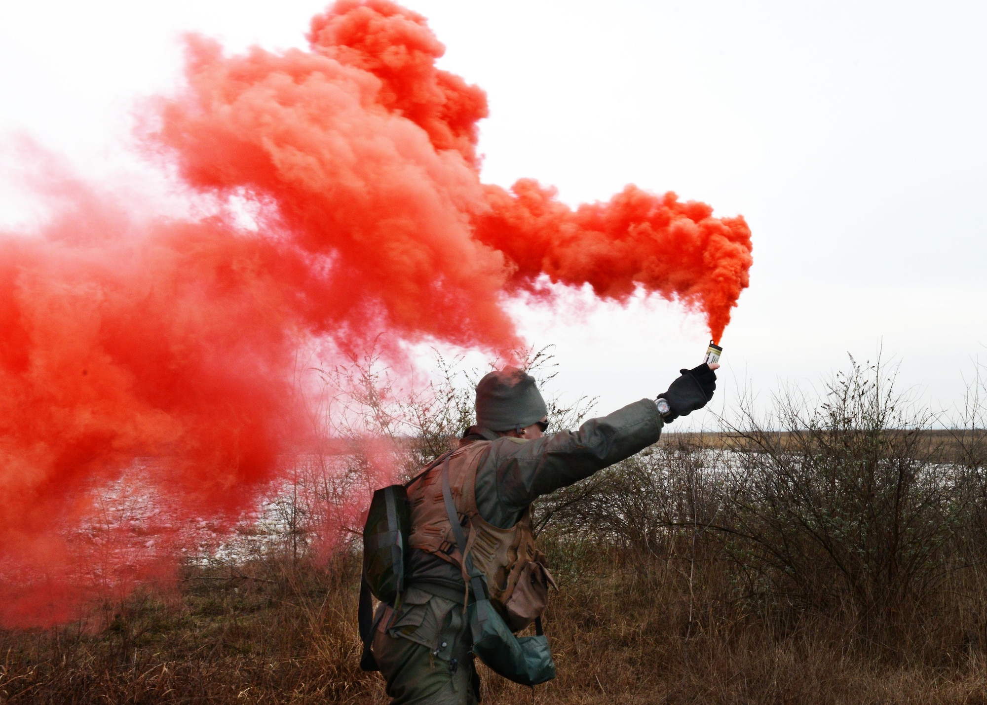 Lt. Col. Christopher Austin, 510th Fighter Squadron commander, utilizes red distress smoke to signal his location to a U.S. Army 12th Combat Aviation Brigade UH-60 Black Hawk helicopter during a simulated combat search and rescue, Jan. 28, 2014, at Cellina Meduna training grounds near Maniago, Italy.  (U.S. Air Force/Airman 1st Ryan Conroy) 
