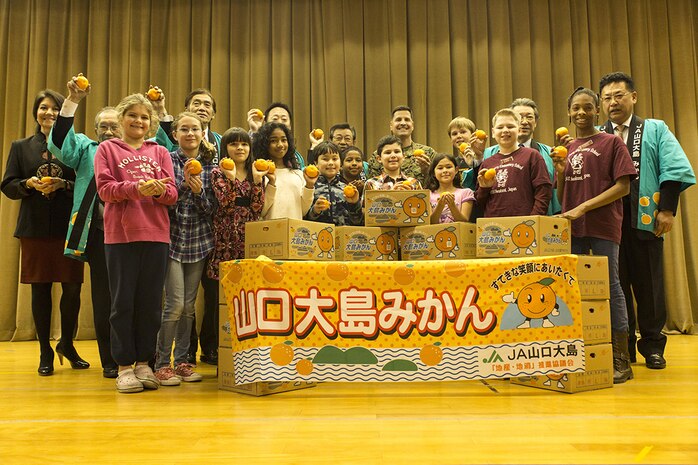 Iwakuni Mayor Yoshihiko Fukuda and several members of the local Iwakuni Agricultural and Societal Cooperative Associations pose for a picture with members of the Student Council with Matthew C. Perry Elementary School during a mikan-presentation at the M.C. Perry elementary gymnasium aboard Marine Corps Air Station Iwakuni, Japan, Jan. 30, 2014. The purpose of the event was to build a better sense of appreciation and understanding between Iwakuni residents and the M.C. Perry students. The local Iwakuni Agricultural and Societal Cooperative Associations presented M.C. Perry Elementary School with 20 boxes of mikans with an approximately value of 100,000 yen.