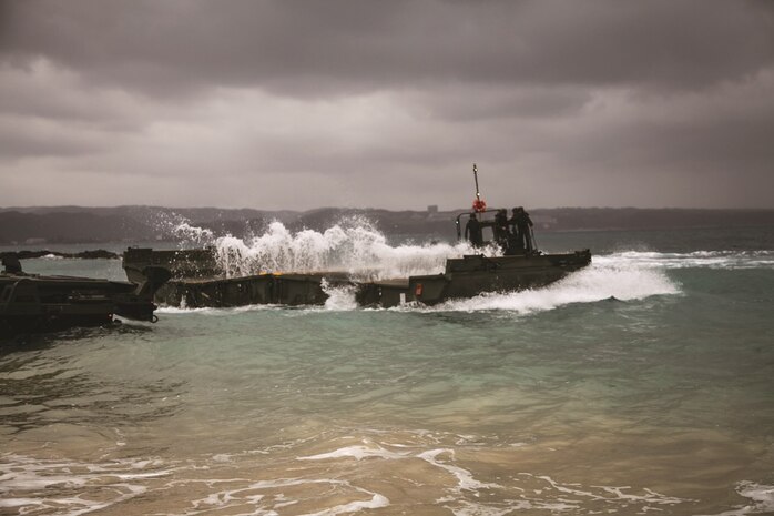 Marines observe as a bay from the new improved ribbon bridge splashes open at Camp Schwab, Feb. 6 during new equipment training. The five days of training enabled the Marines to build on their previous knowledge of
bridges and learn the fundamentals of the IRB and Marine Corps bridge pallet system. The Marines are with 9th
Engineer Support Battalion, 3rd Marine Logistics Group, III Marine Expeditionary Force.