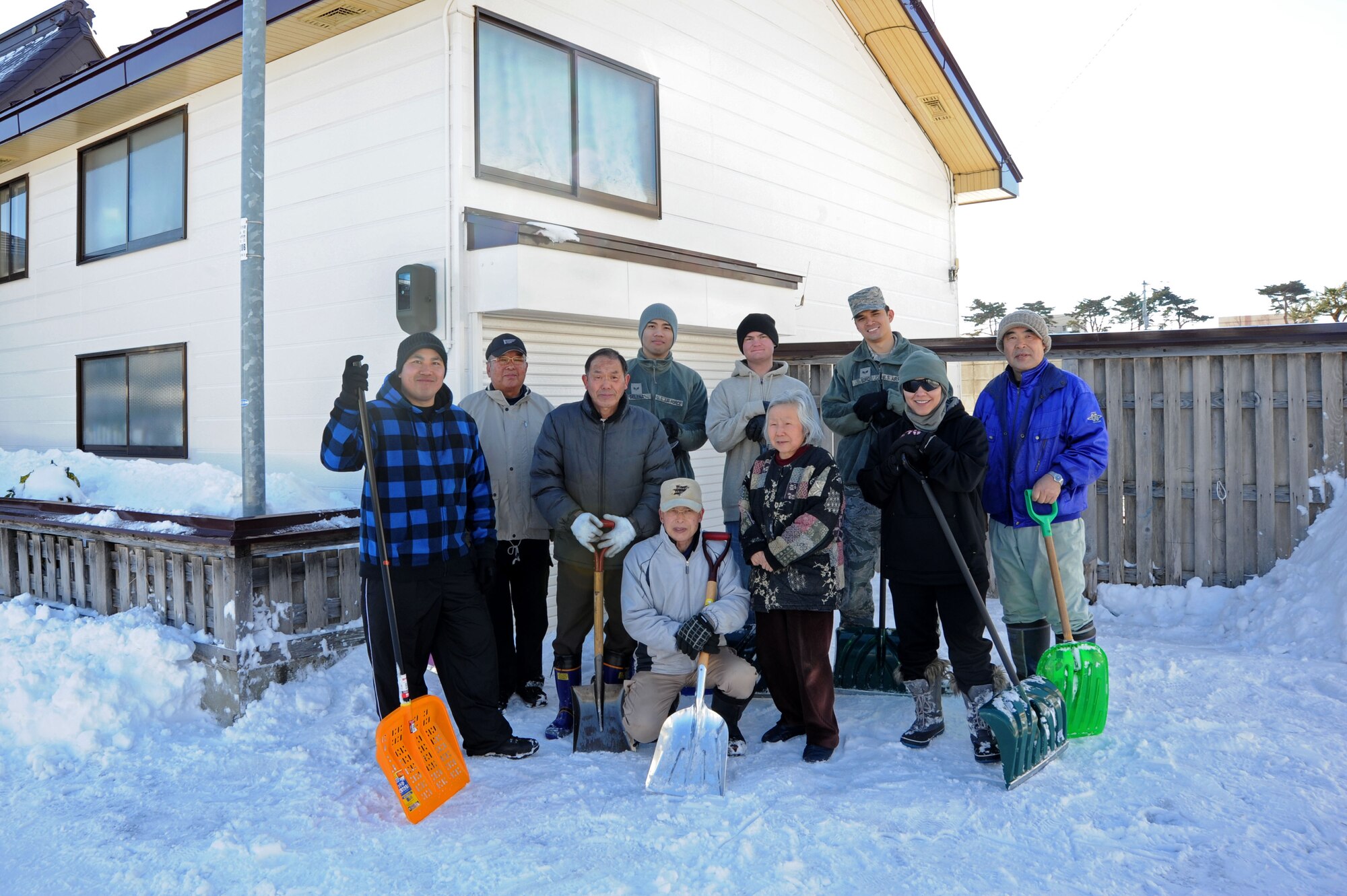 U.S. Air Force Airmen and Misawa Social Welfare Center members pose with an elderly homeowner after removing snow from around her house in Misawa City, Japan, Feb. 11, 2014.  Service members took time out of their day to give back to the elderly members of the community by clearing sidewalks and driveways.(U.S. Air Force photo/Tech. Sgt. April Quintanilla)