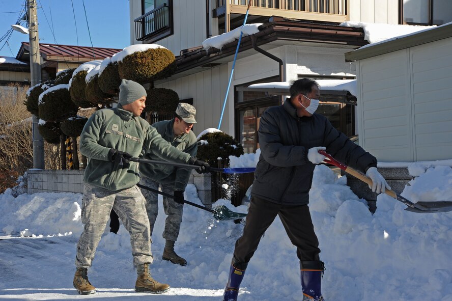 Senior Airmen Englebert Delena and James Lord, 35th Medical Group diagnostic imaging technicians, and a member of the Misawa Social Welfare Center remove snow from the house of an elderly community member in Misawa City, Japan, Feb. 11, 2014.  This outreach project allows Misawa Airmen to show their commitment to helping those in need.  (U.S. Air Force photo/Tech. Sgt. April Quintanilla)